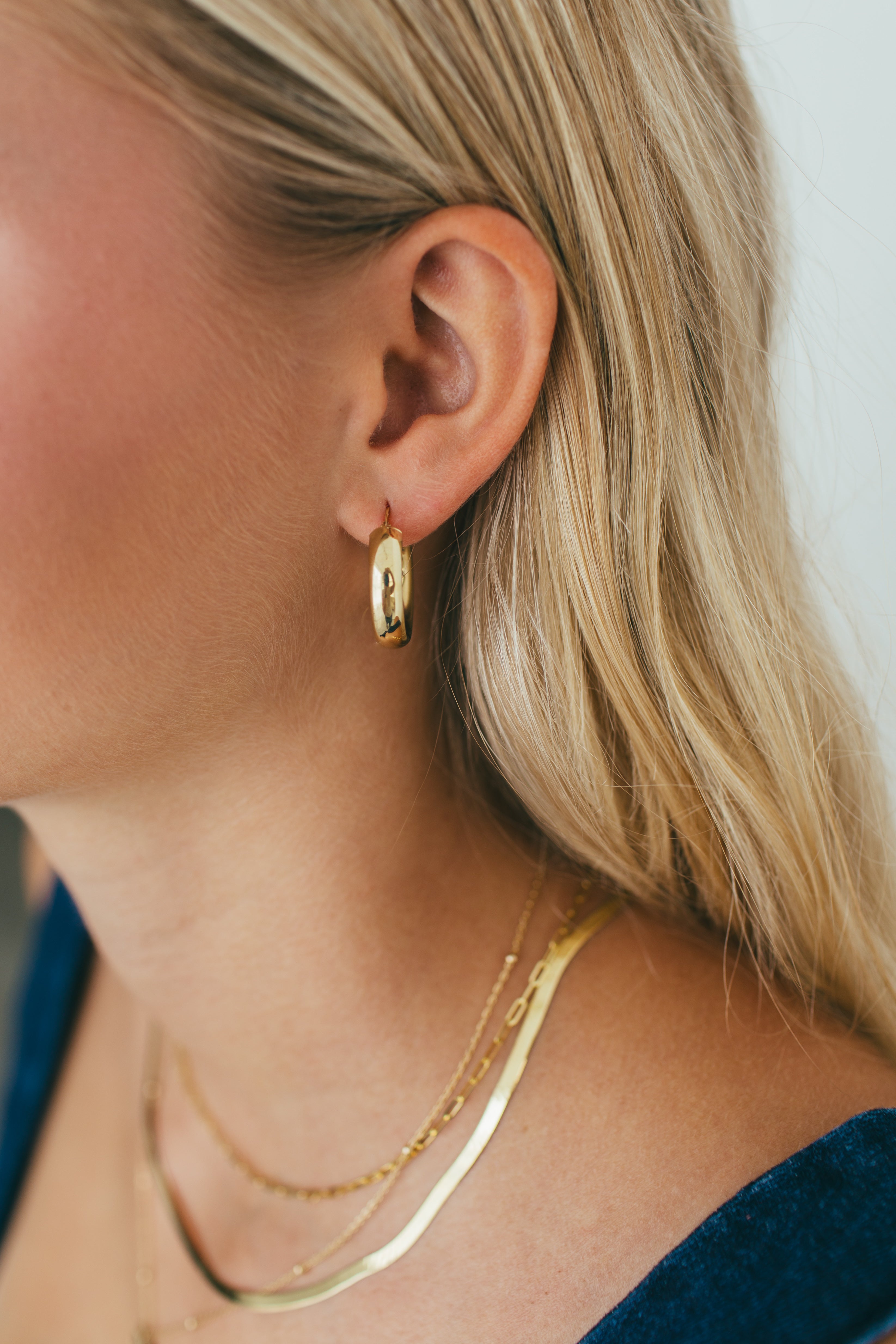 close up of girls ear wearing thick large hoops