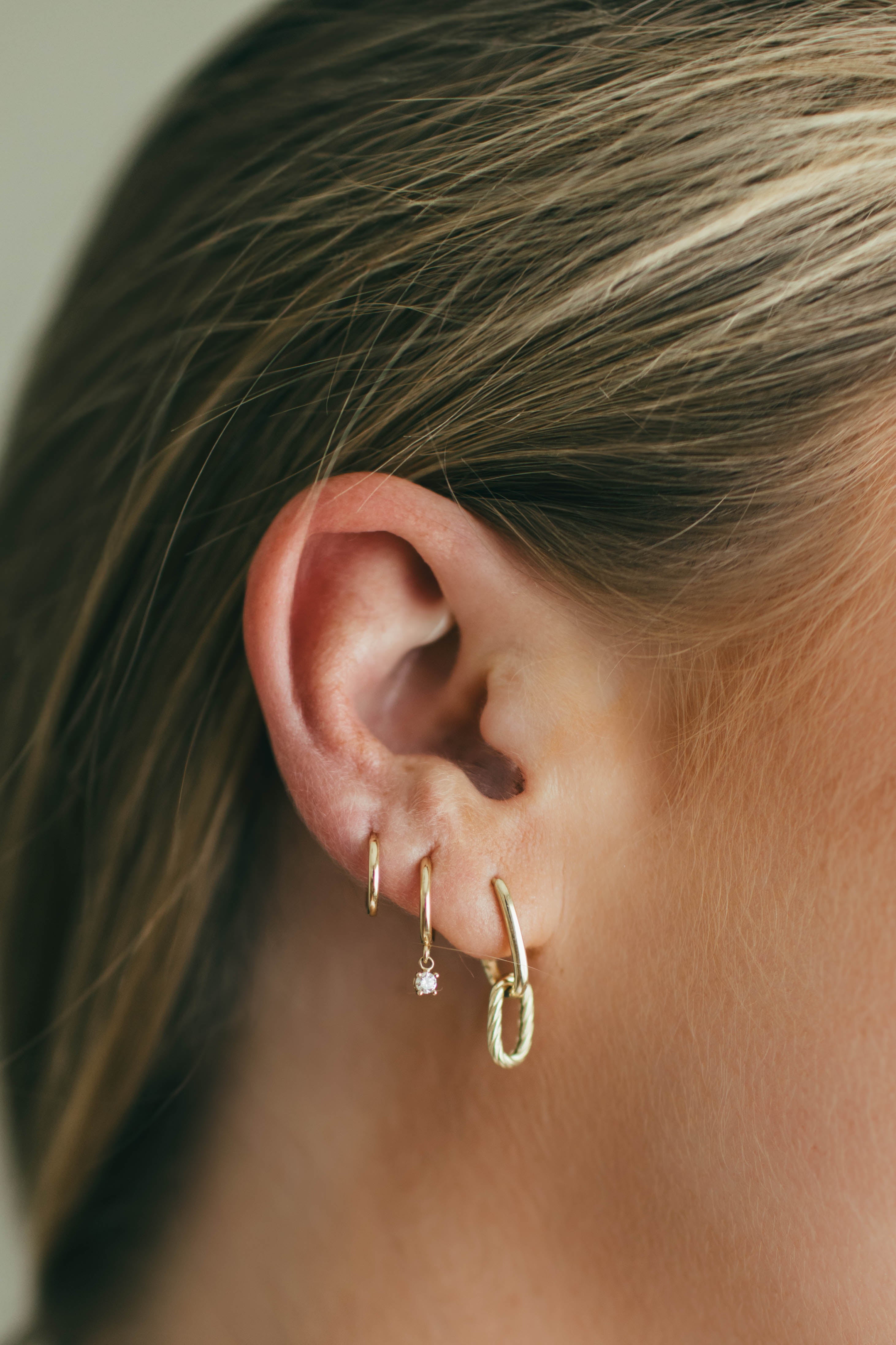 Close-up of an ear wearing gold hoop earrings with a blurred background