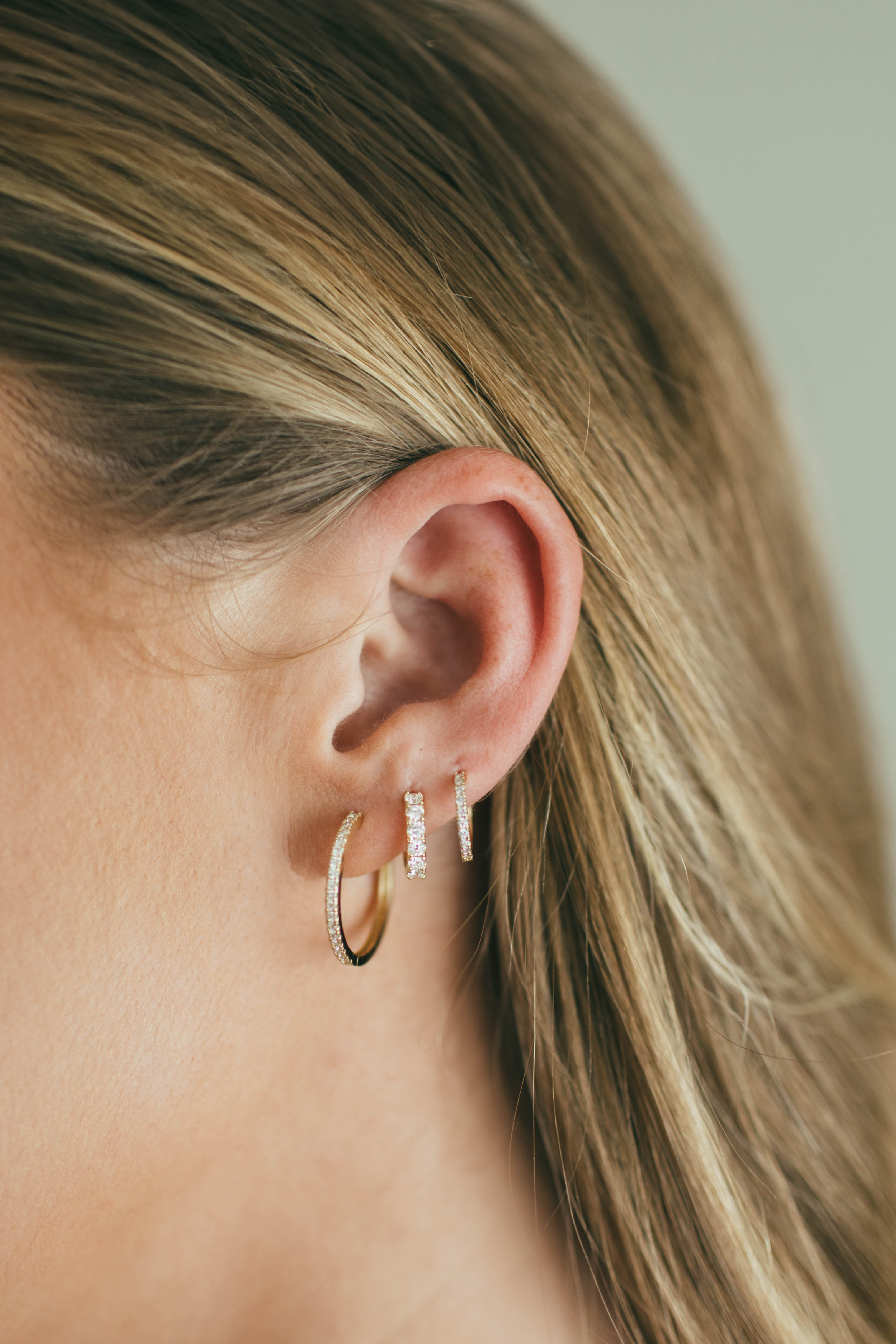 Close-up of a person wearing gold hoop earrings with a blurred background