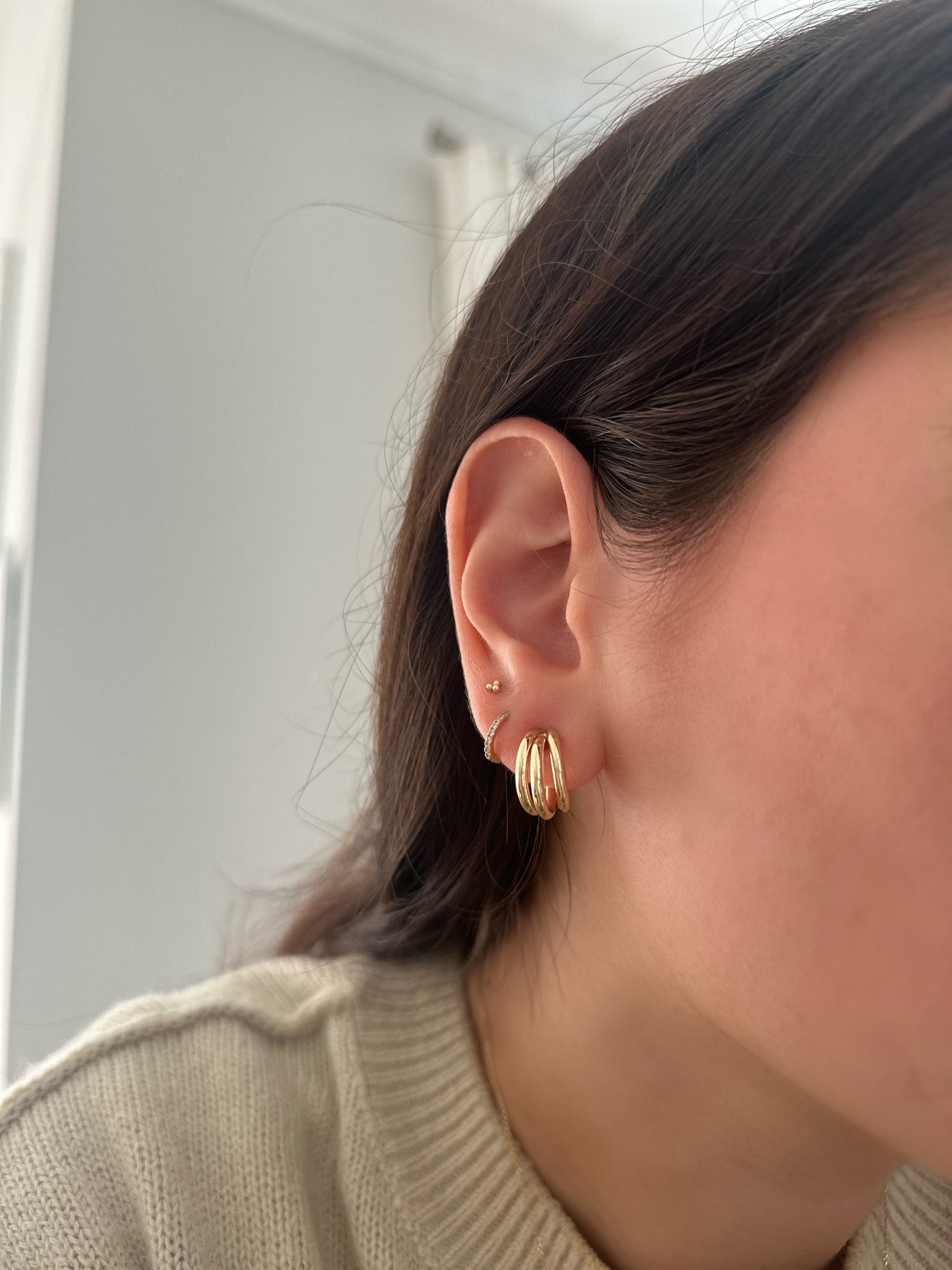 close up of girl wearing gold earring stack