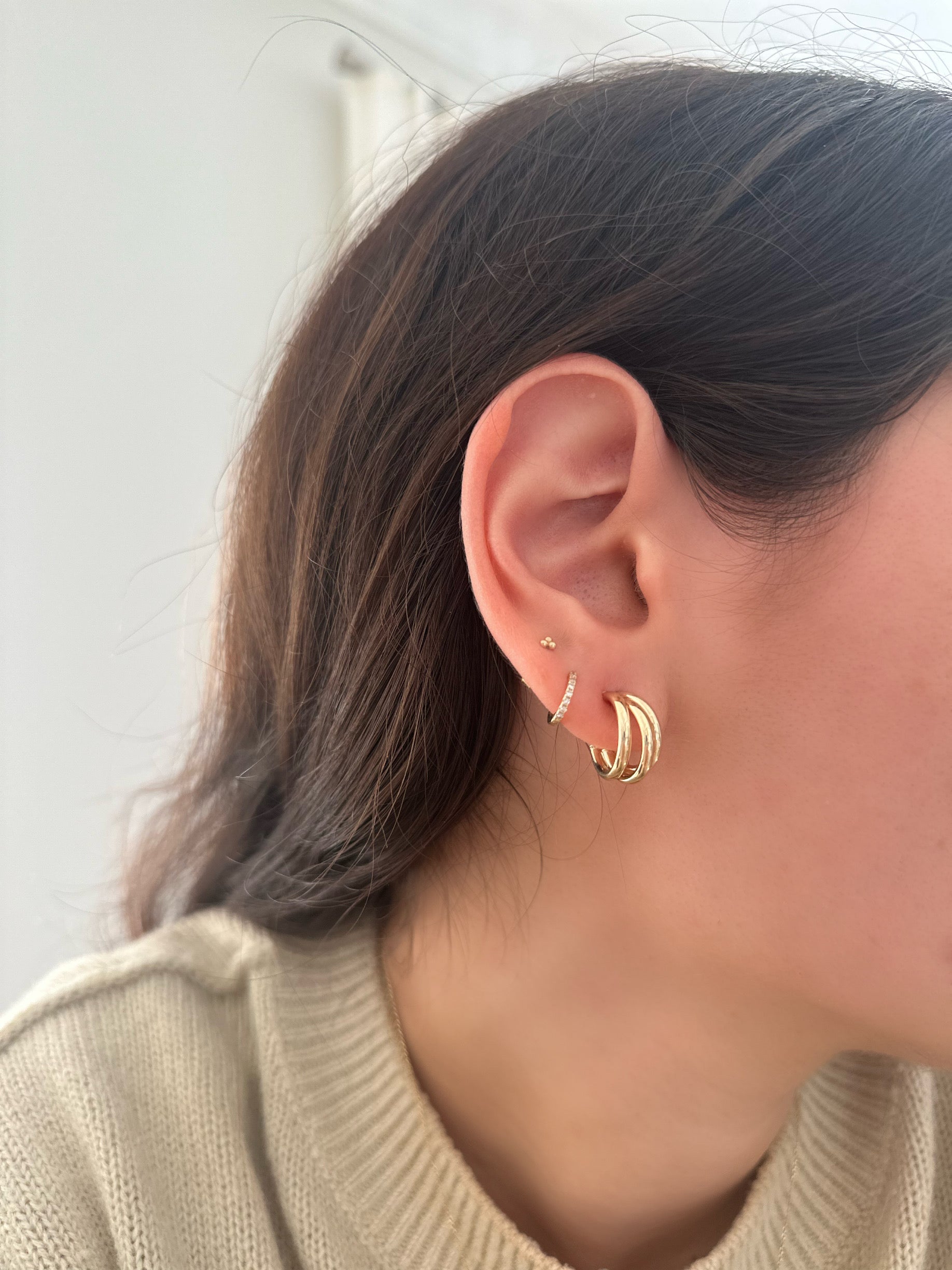 side profile of girl wearing gold earring stack