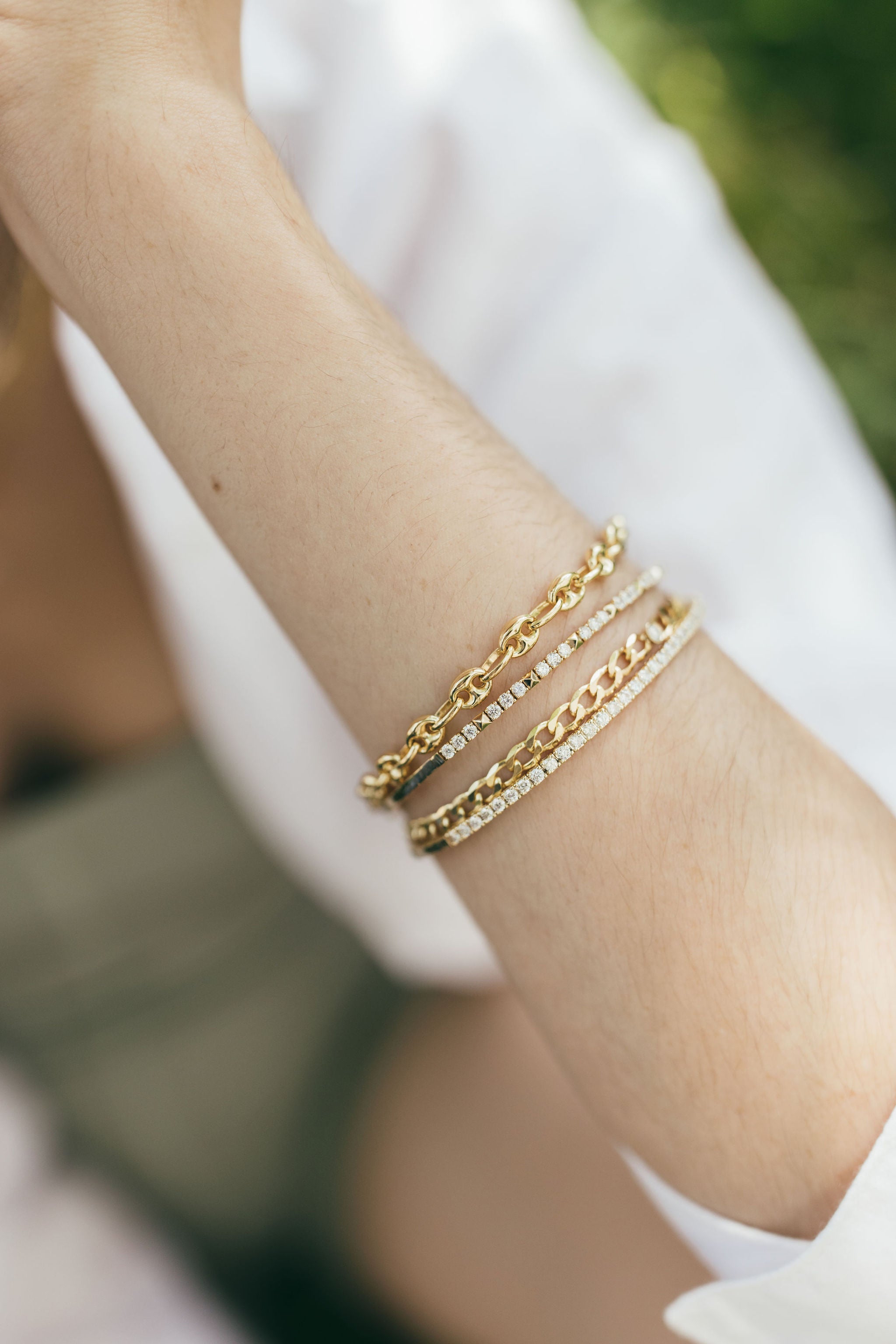 Stack of gold and diamond bracelets on arm