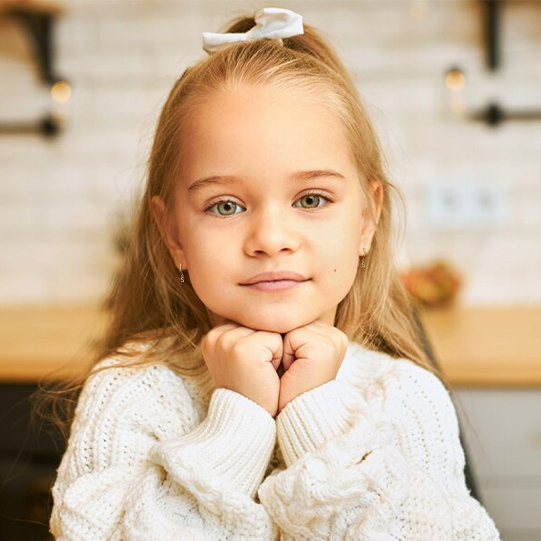 little girls wearing gold dangling initial huggies