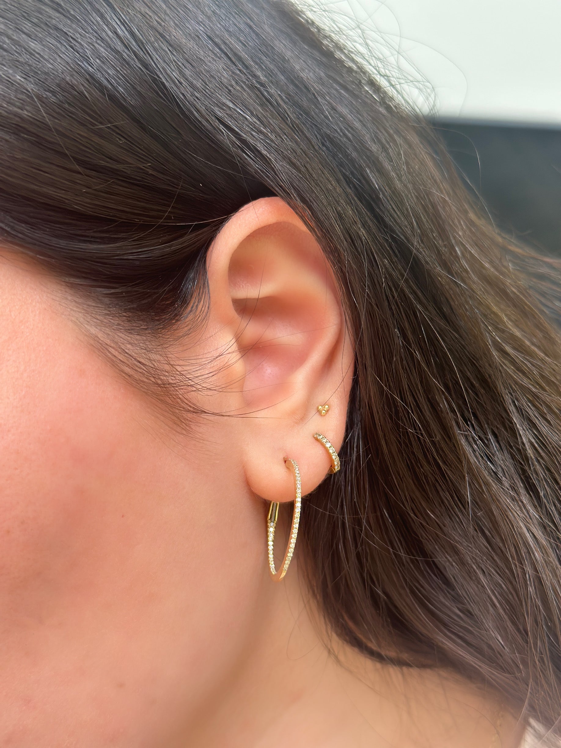 close up of girls ear wearing yellow gold diamond hoops
