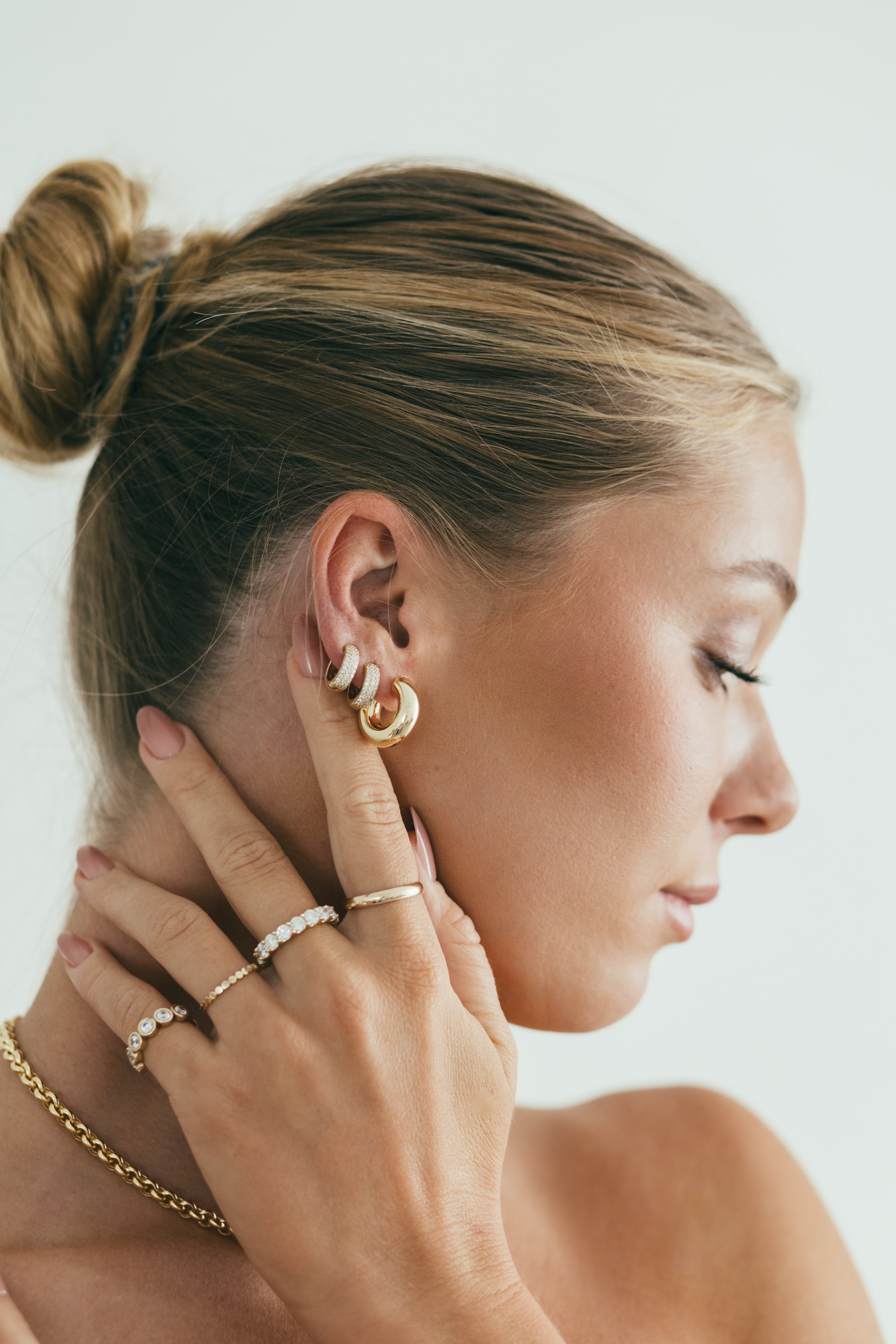 side profile of girl wearing diamond earring stack and diamond ring stack