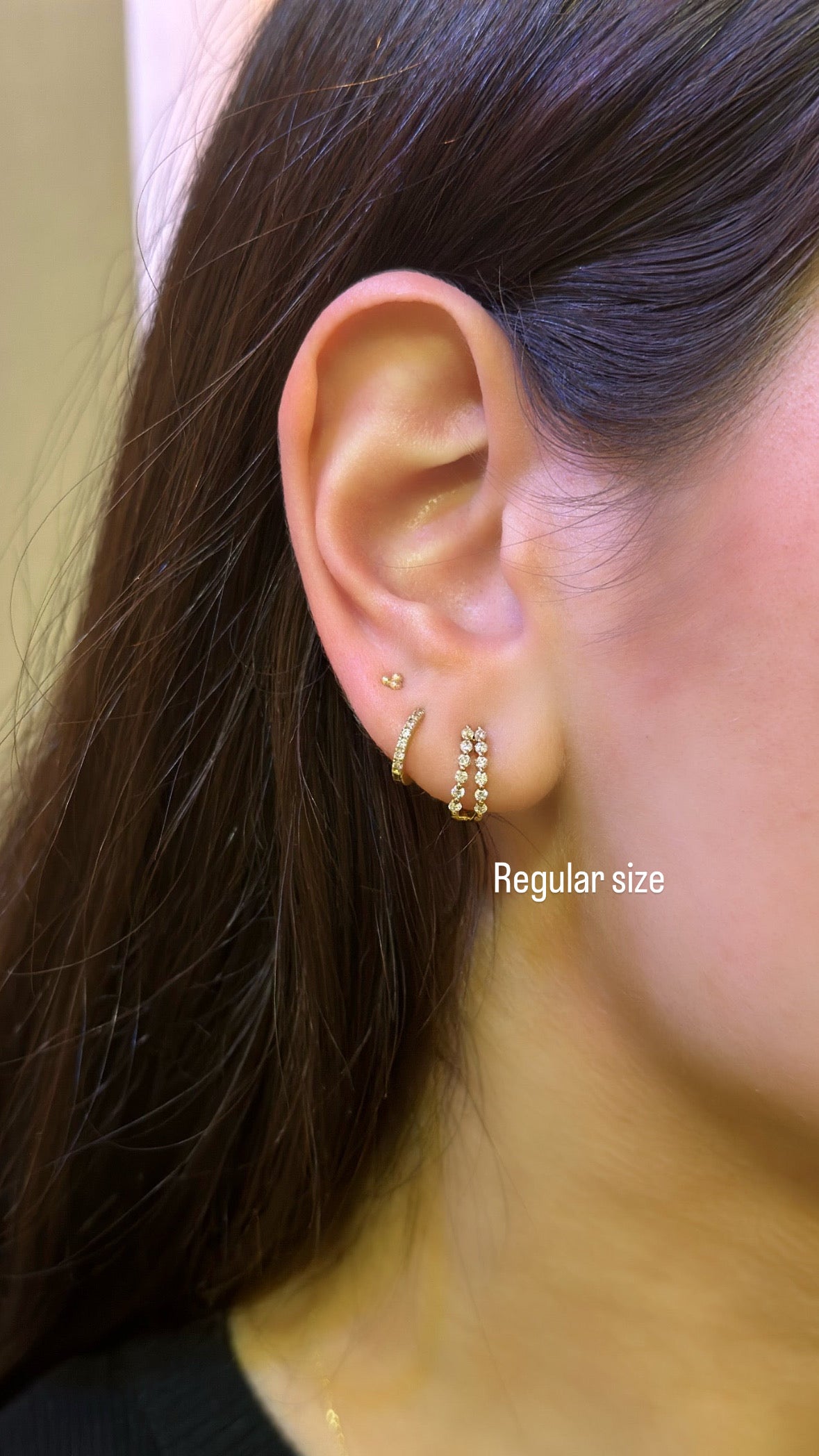 close up of ear displaying the regular size of the single prong double diamond huggie earrings