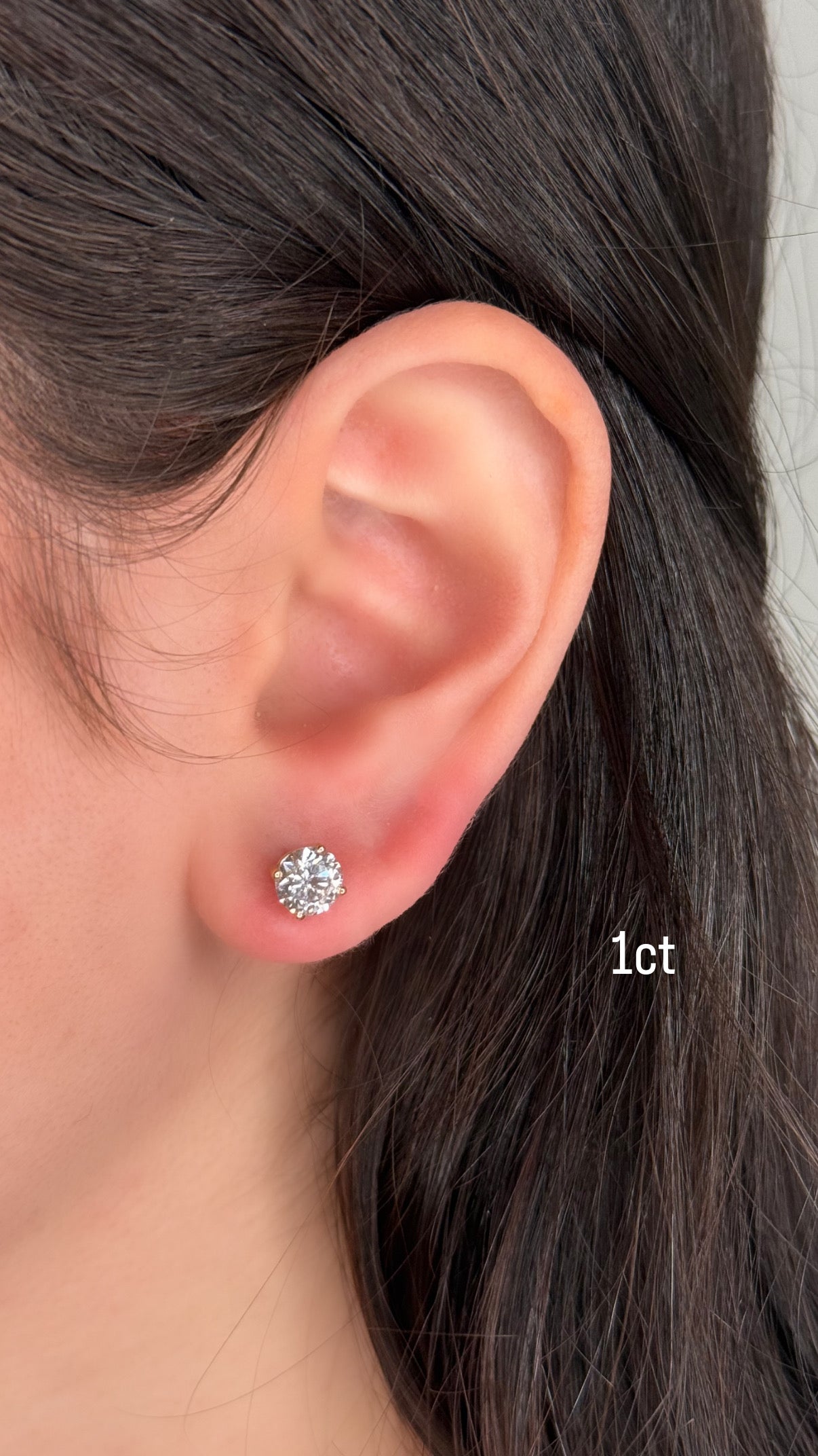 Close-up of an ear wearing a diamond stud earring with hair partially covering the face.