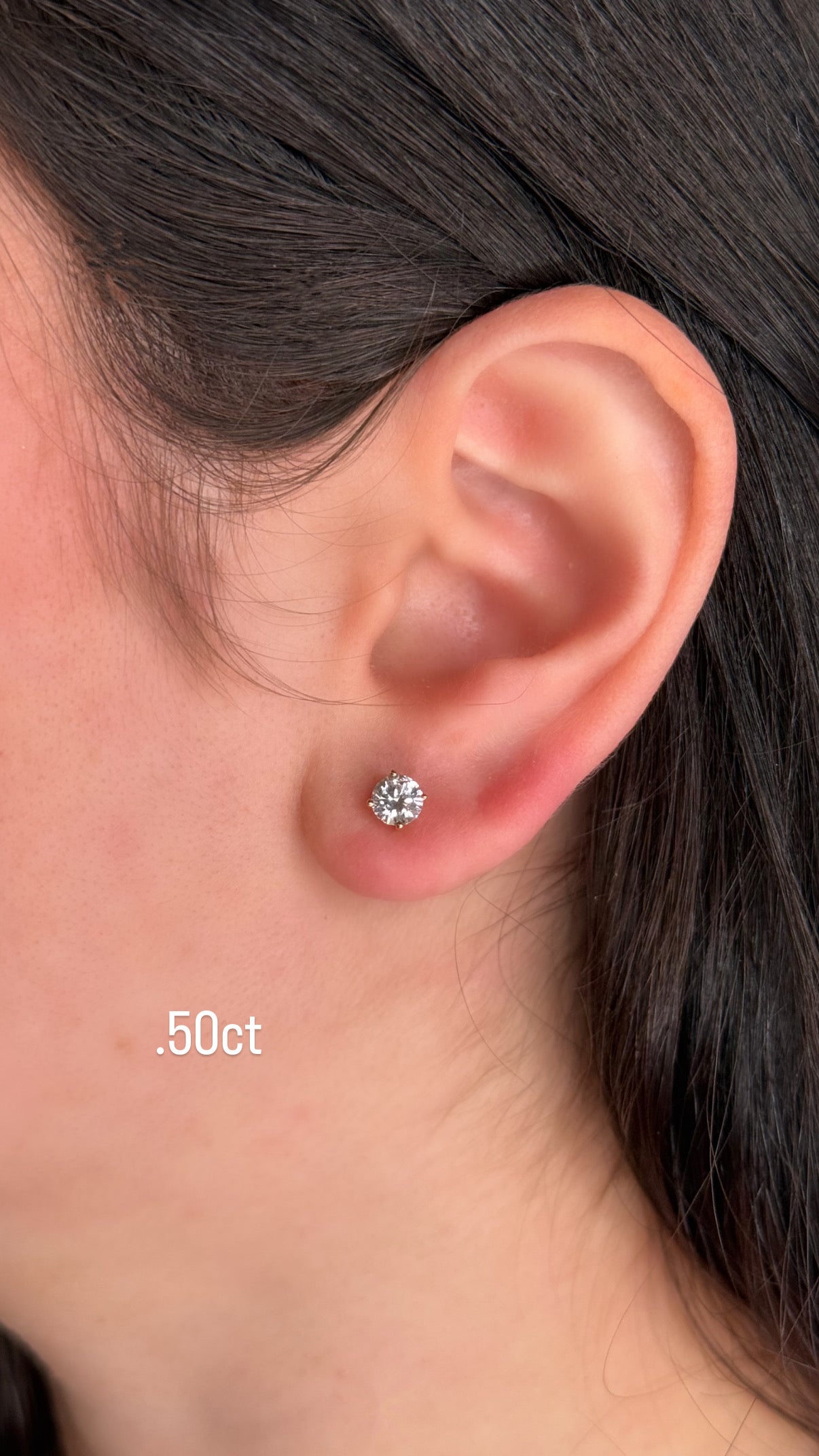 Close-up of an ear wearing a diamond stud earring with '0.50ct' label.