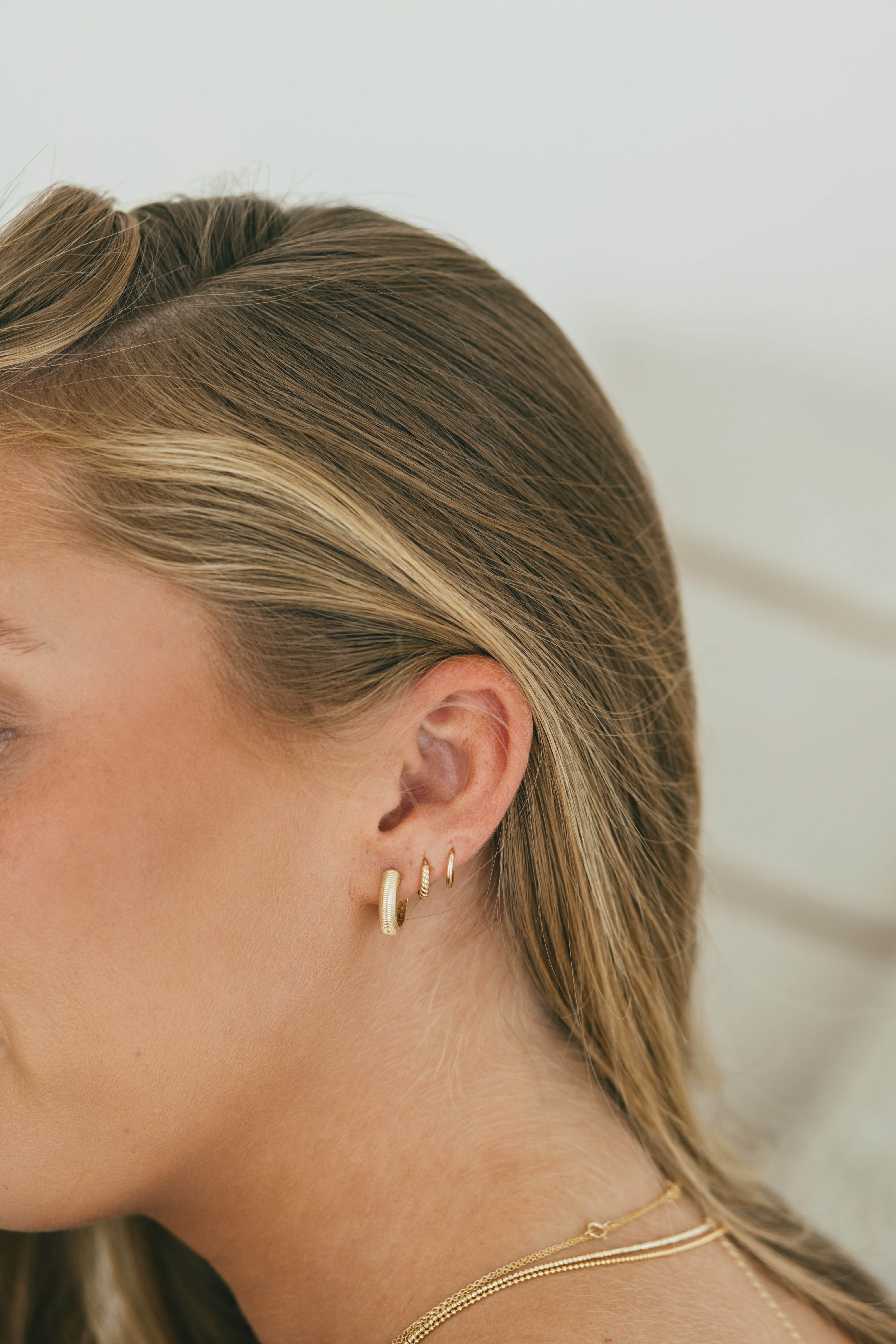 girls ear wearing gold earring huggie stack