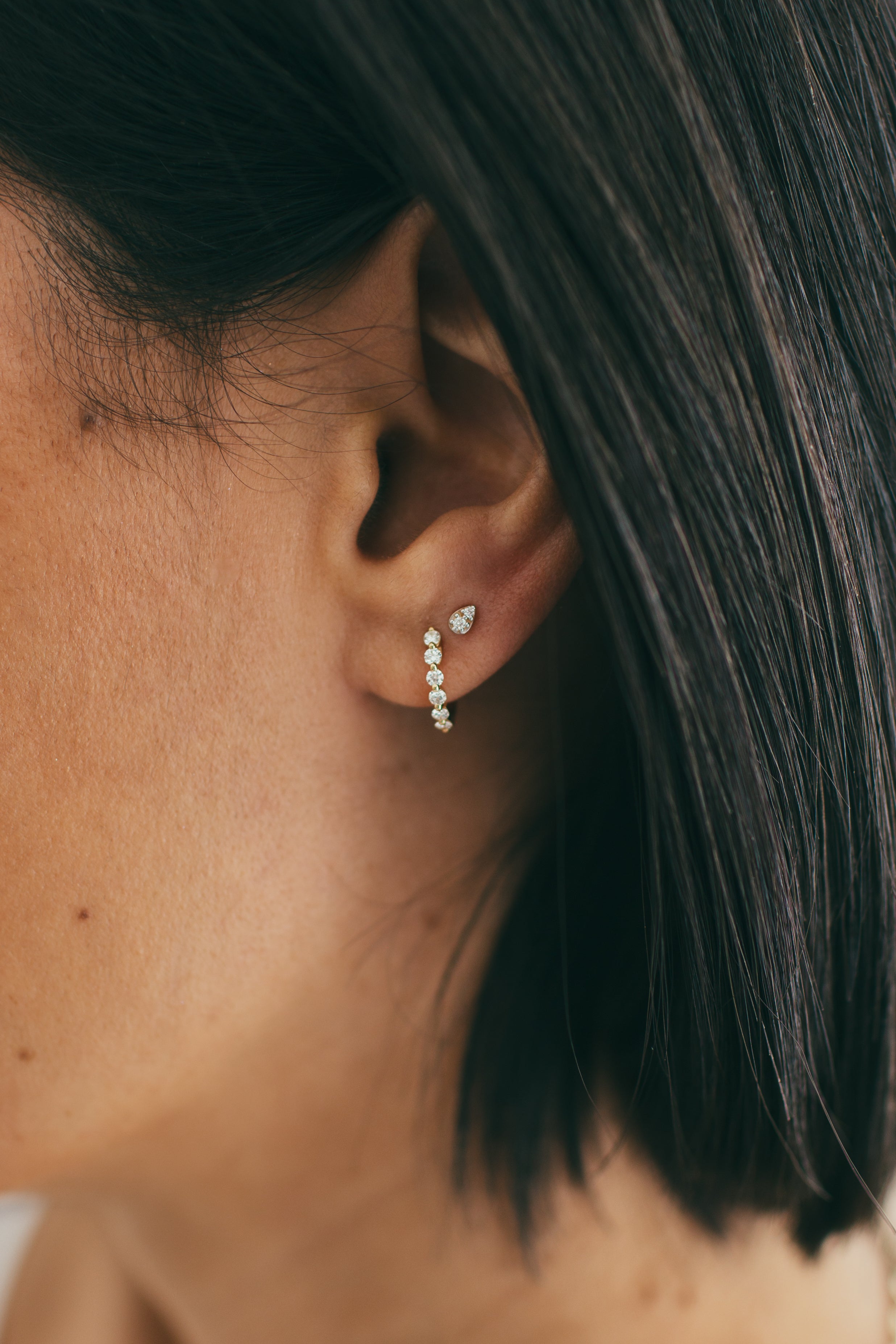 close up of ear wearing diamond huggie and diamond stud