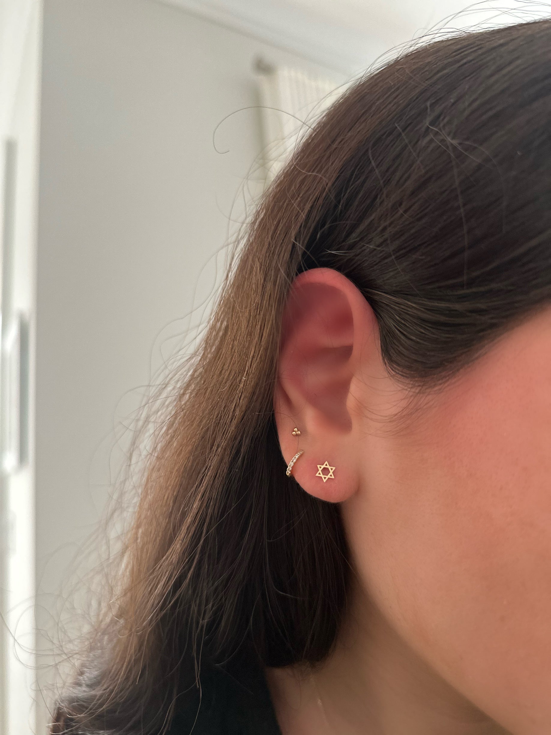 close up of ear wearing 14k gold star of david studs