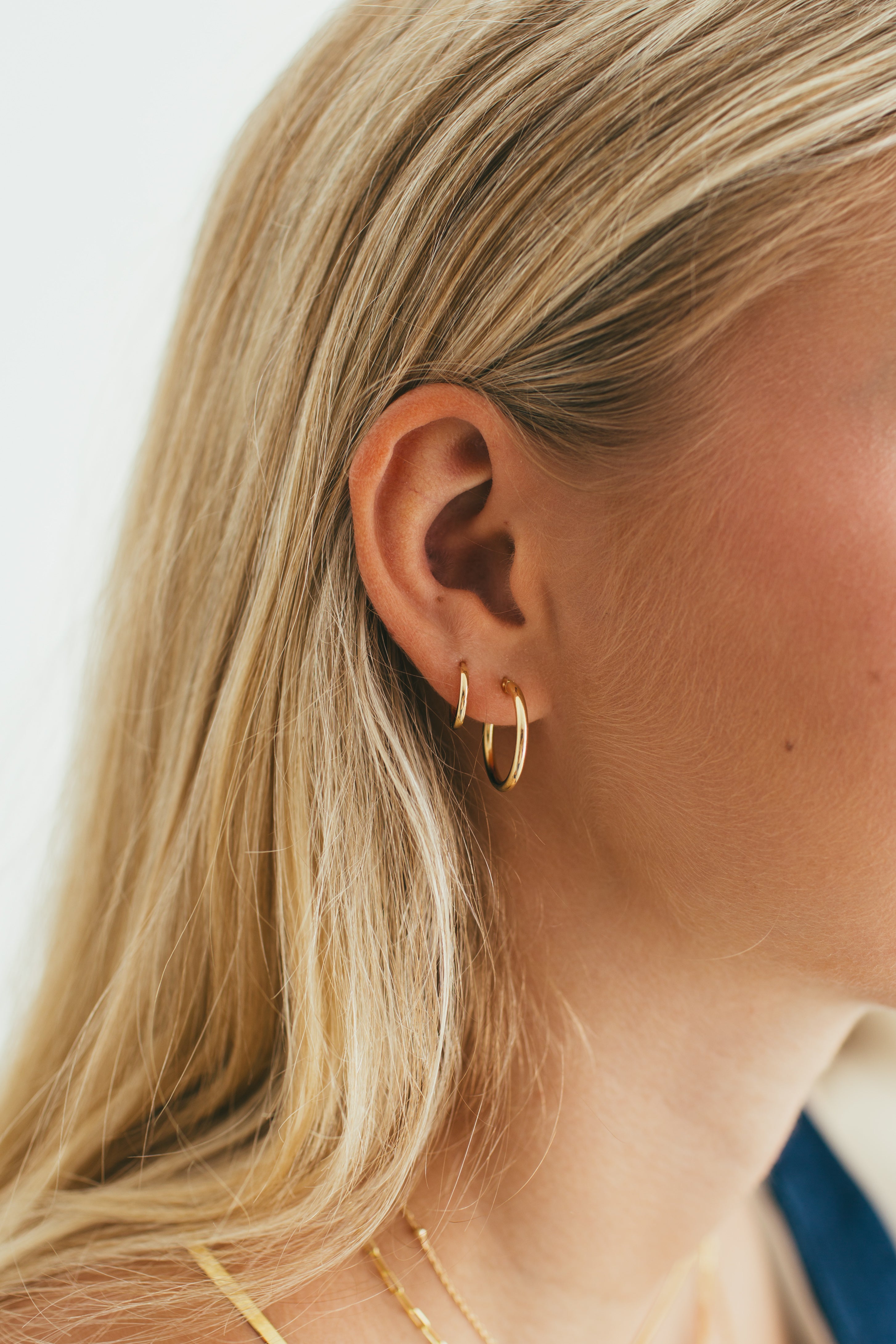 a girl wearing a stack of hoops and gold huggies