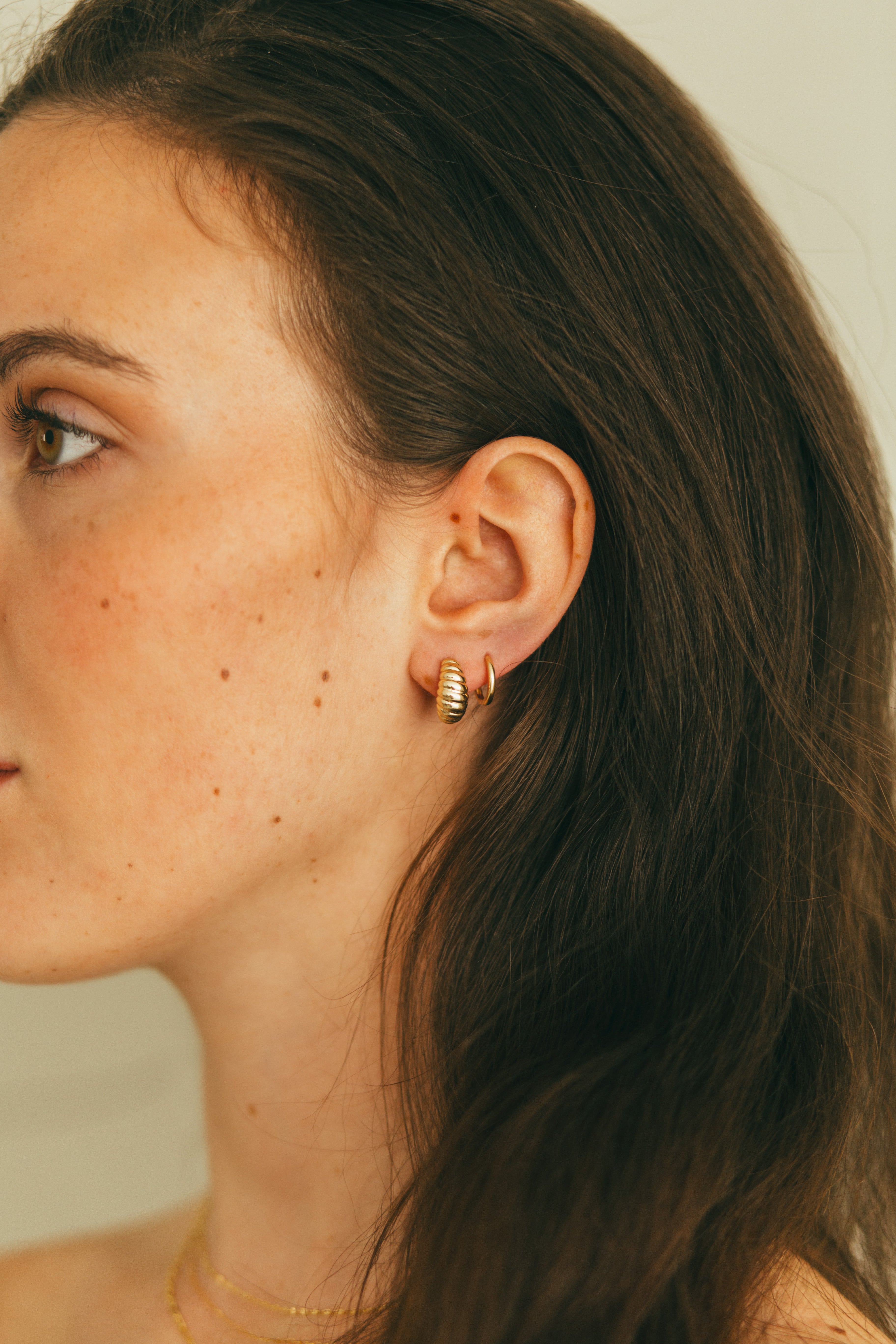 a girl wearing croissant huggies and mini gold huggies