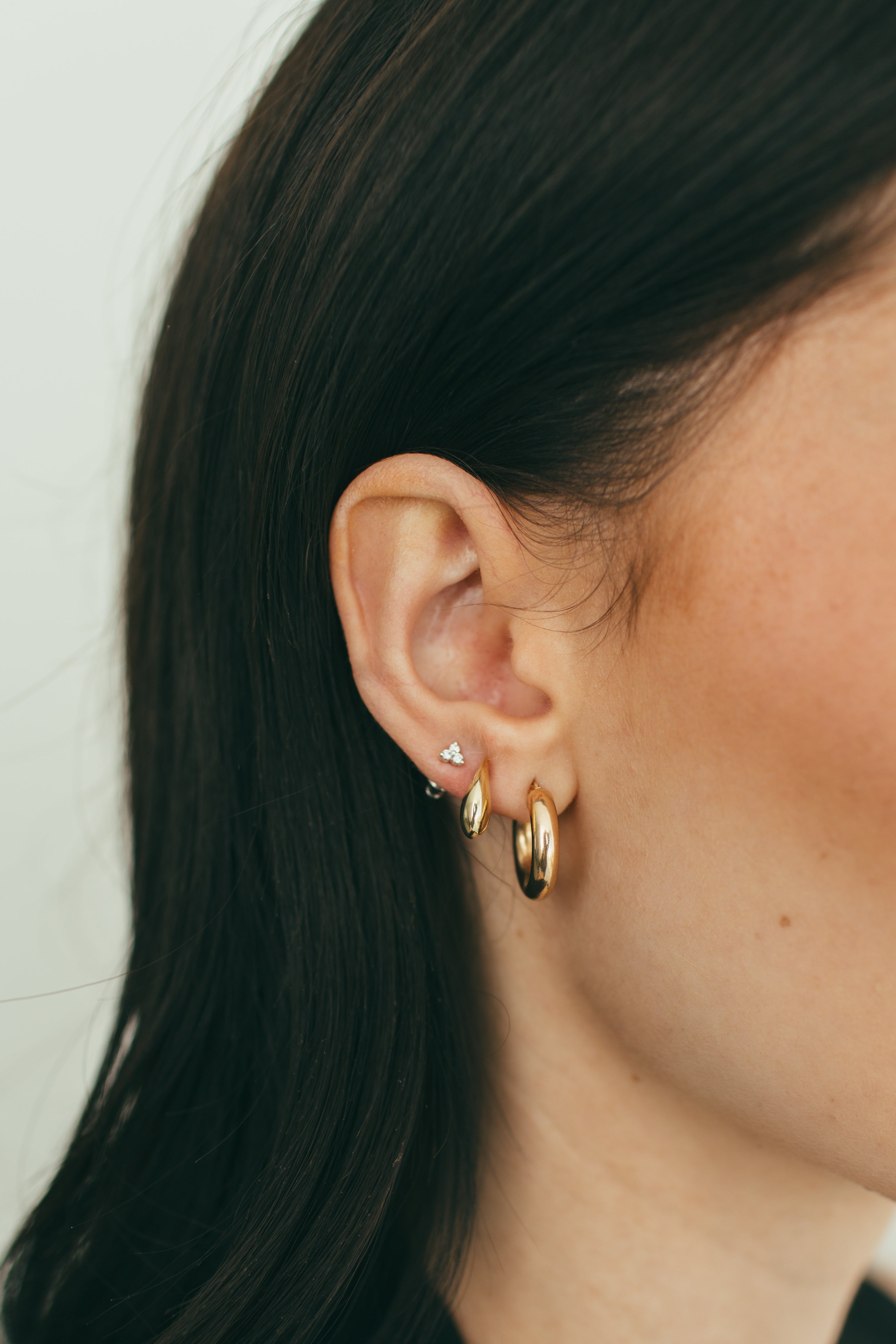 close up of girls ear wearing gold and diamond earring stack