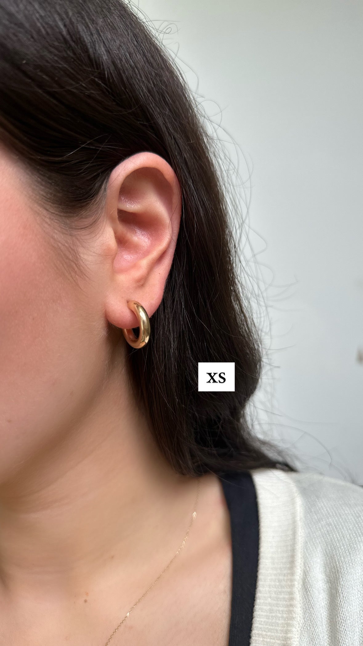 close up of girls ear wearing xs gold hoops