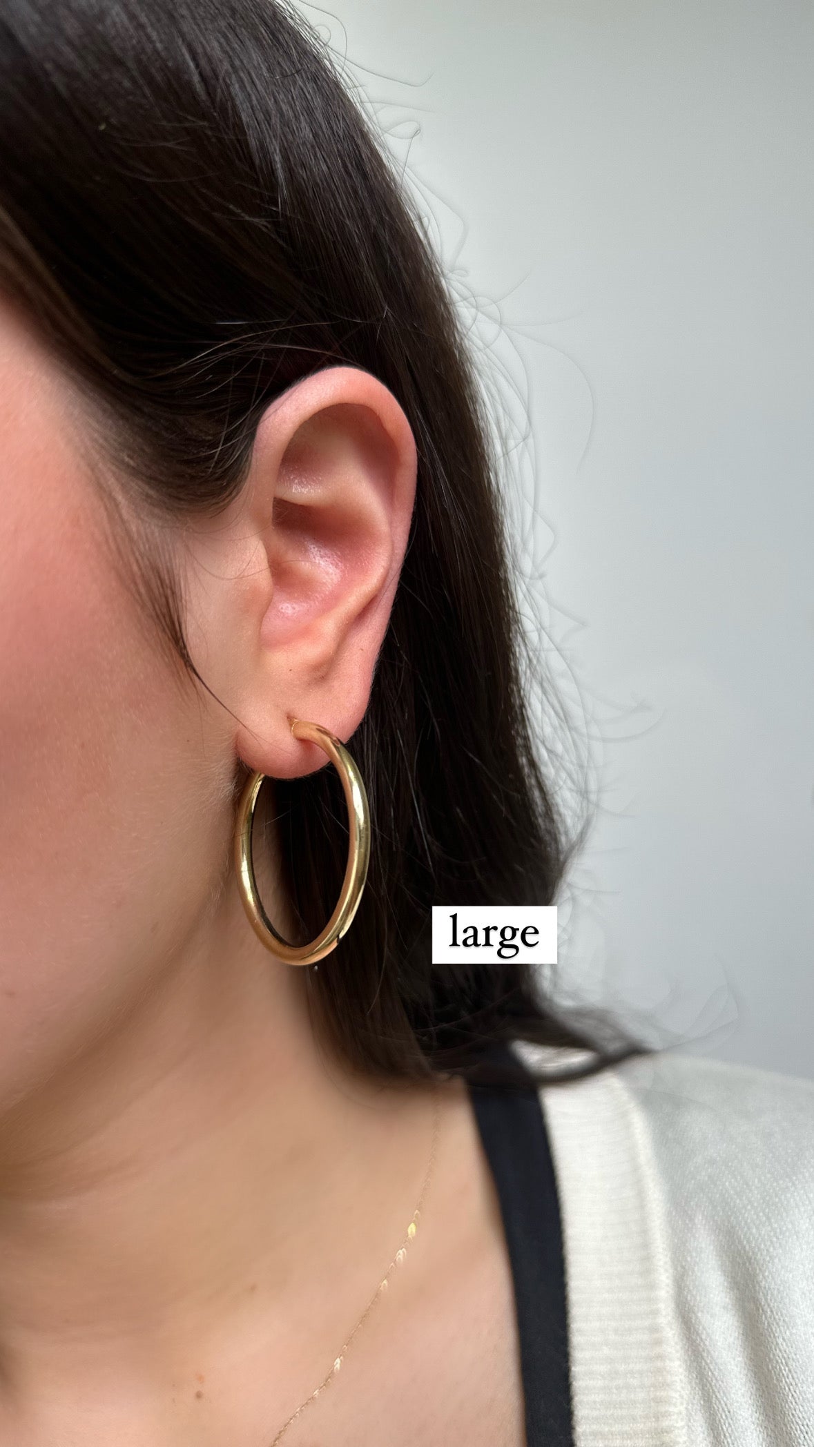 close up of ear wearing large gold hoops