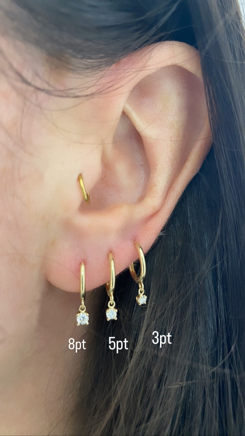 close up of ear displaying 3 different sizes of dangling diamond huggies