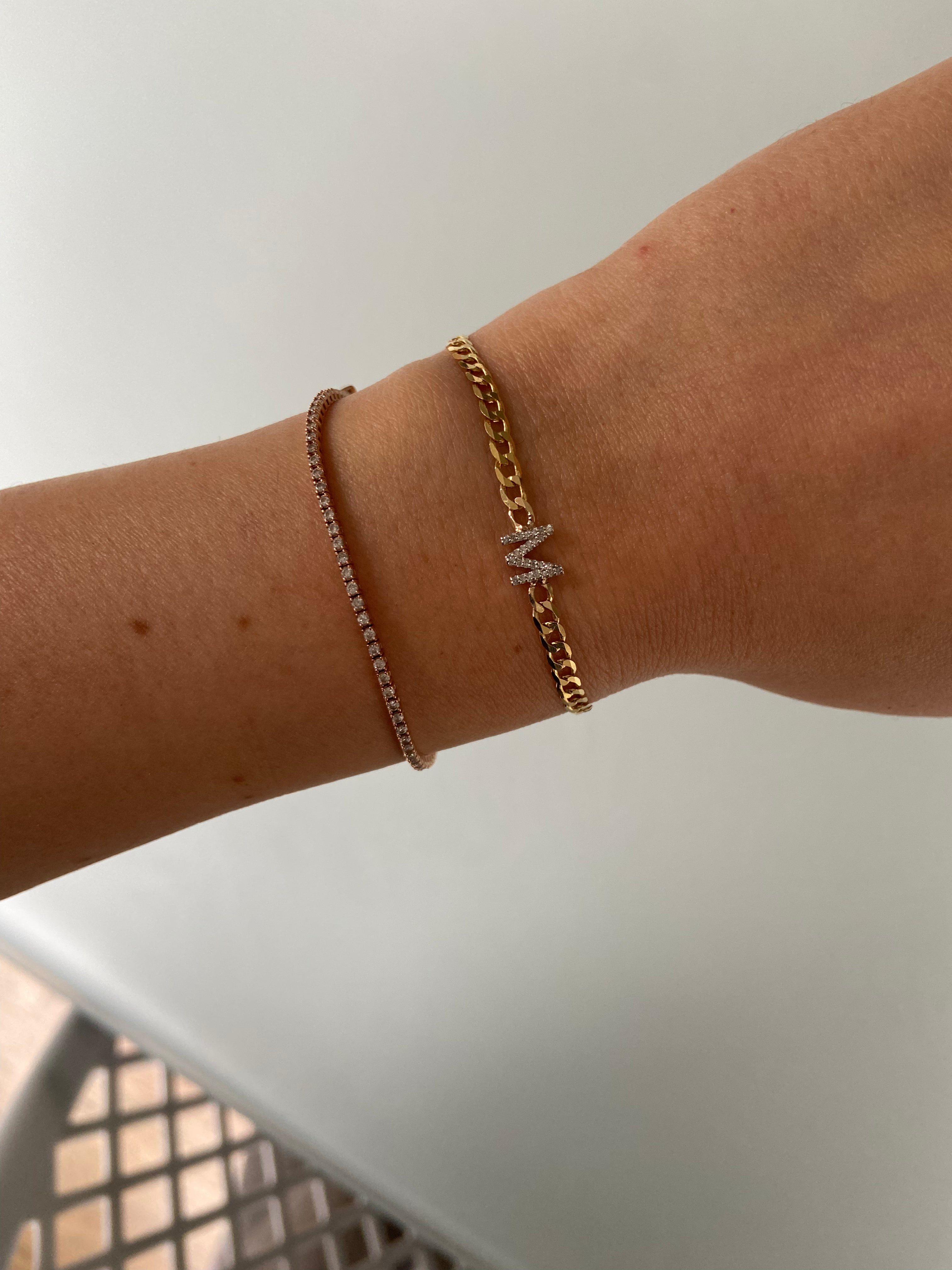 Diamond Initial and Curb Chain Bracelet in yellow gold, stacked with a small tennis bracelet in rose gold.