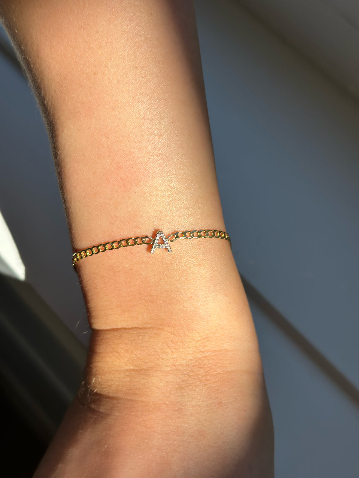 Curb chain bracelet with a diamond A in the center in the sunlight.