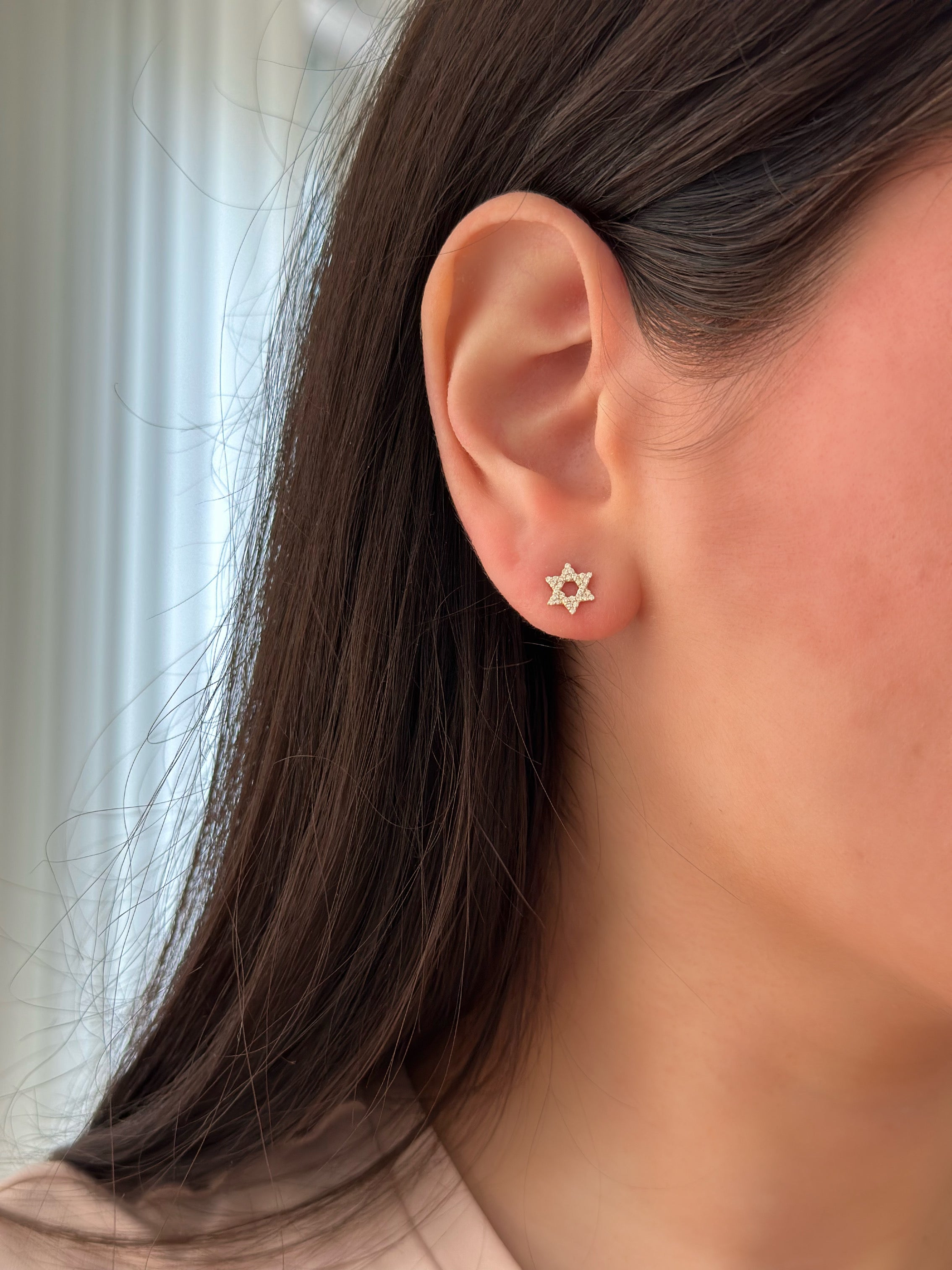 close up of ear wearing diamond star of david studs