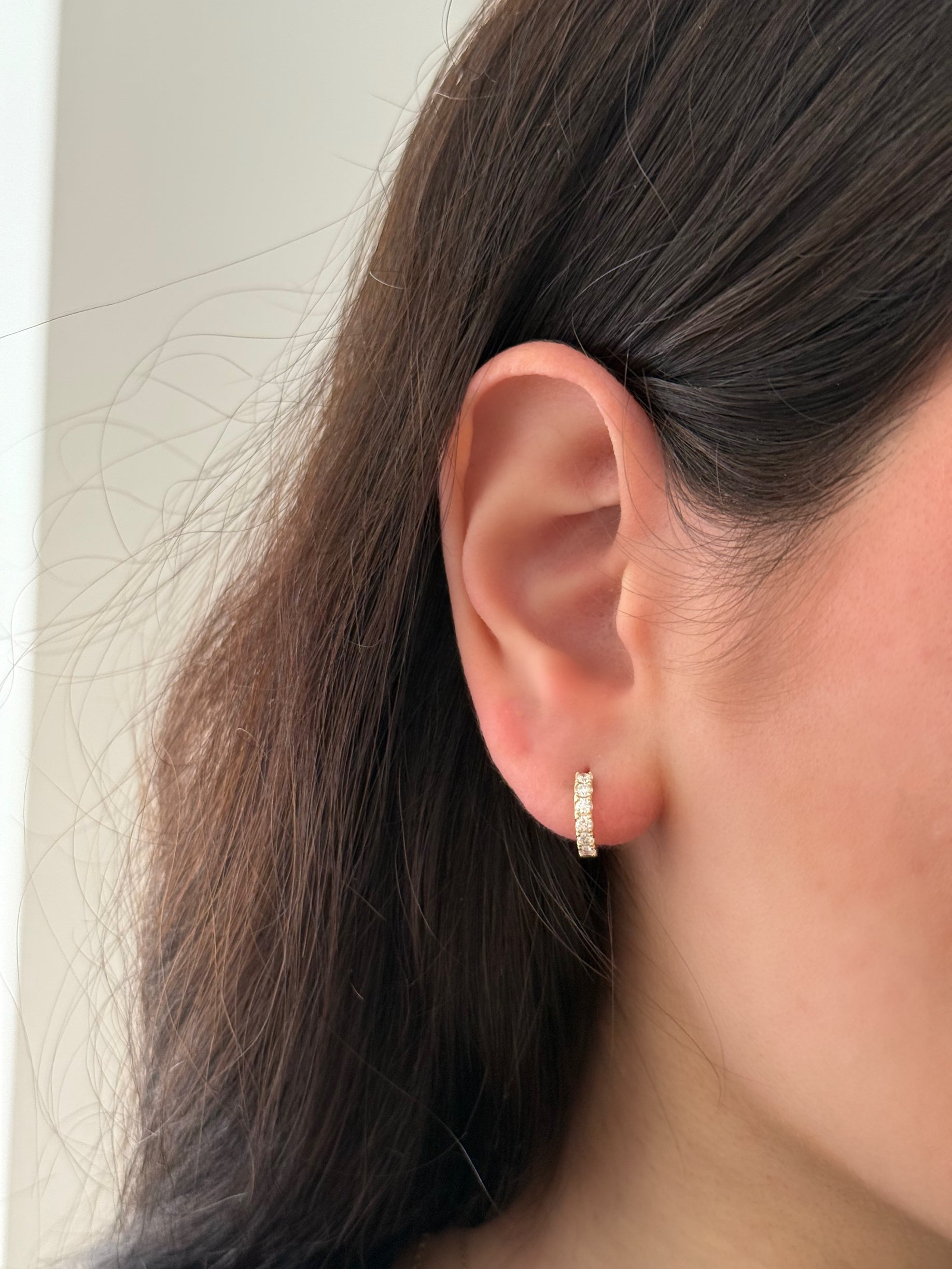 close up of ear wearing yellow gold lab diamond huggies