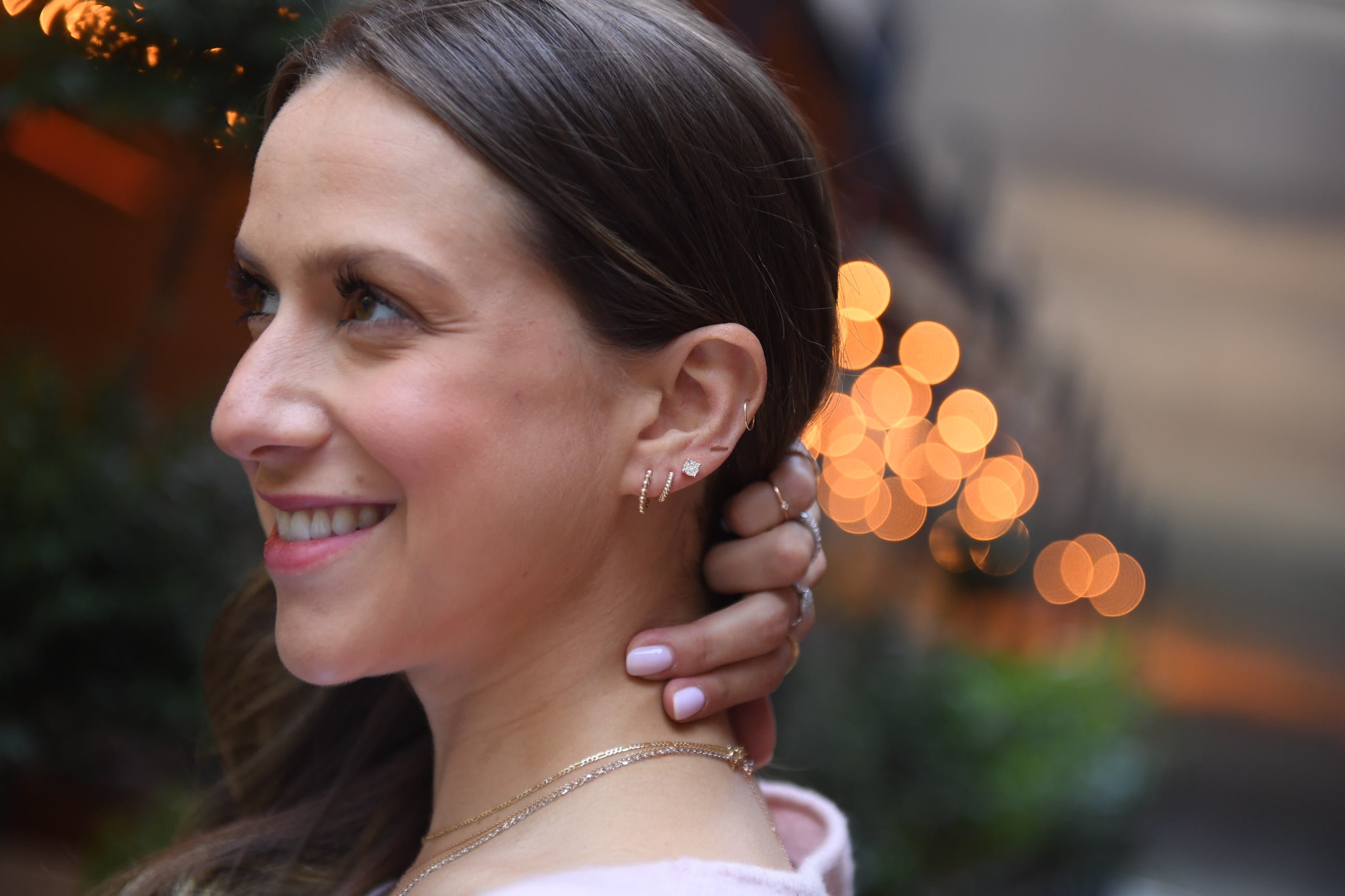 girls smiling wearing a stack of diamond earrings