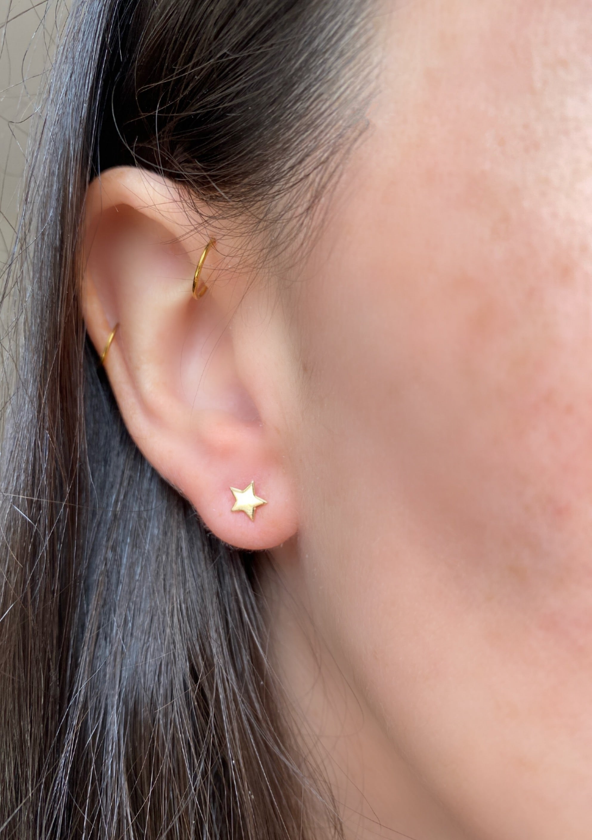 close up of ear wearing gold star studs
