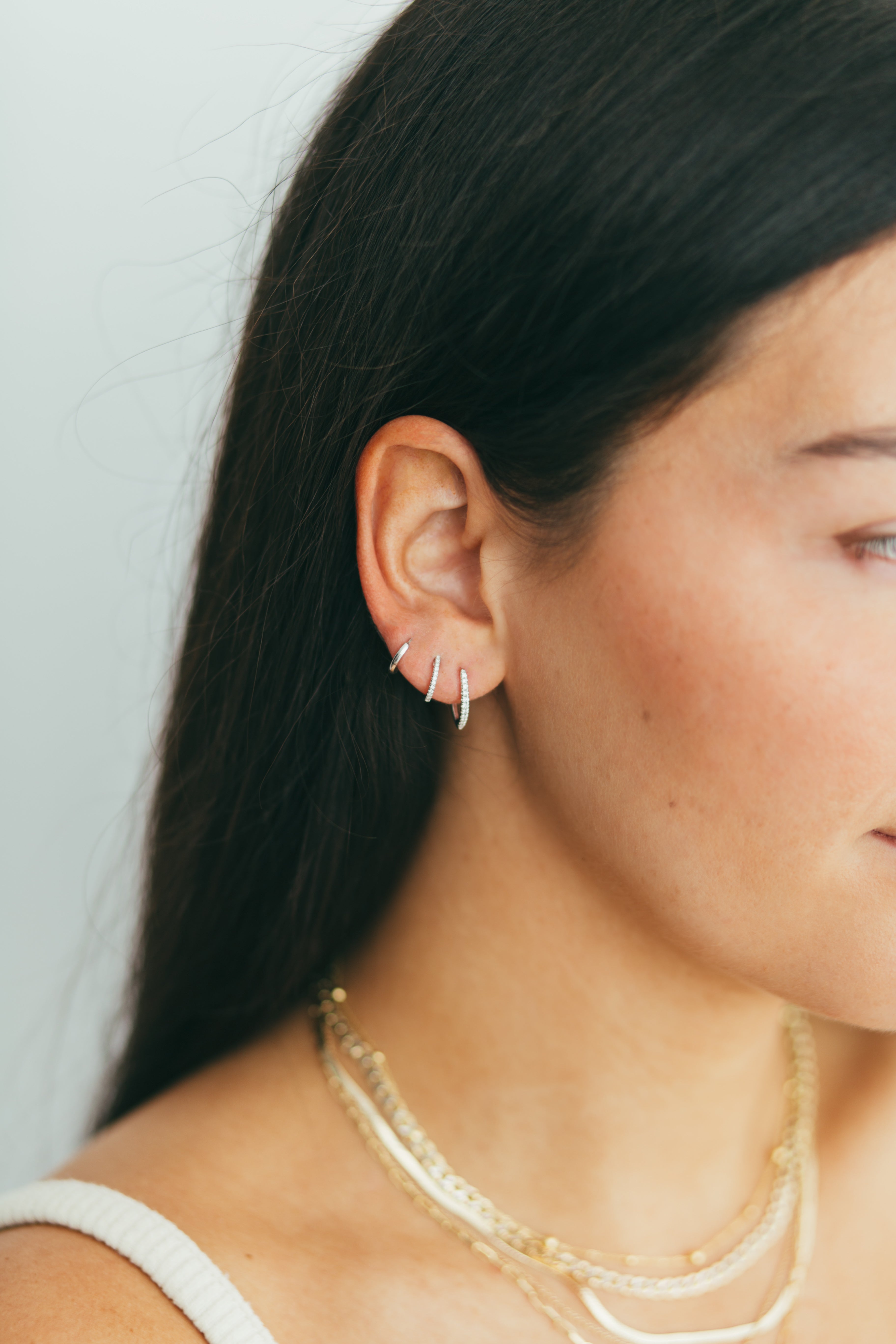 close up of girls ear wearing stack of pave diamond huggies