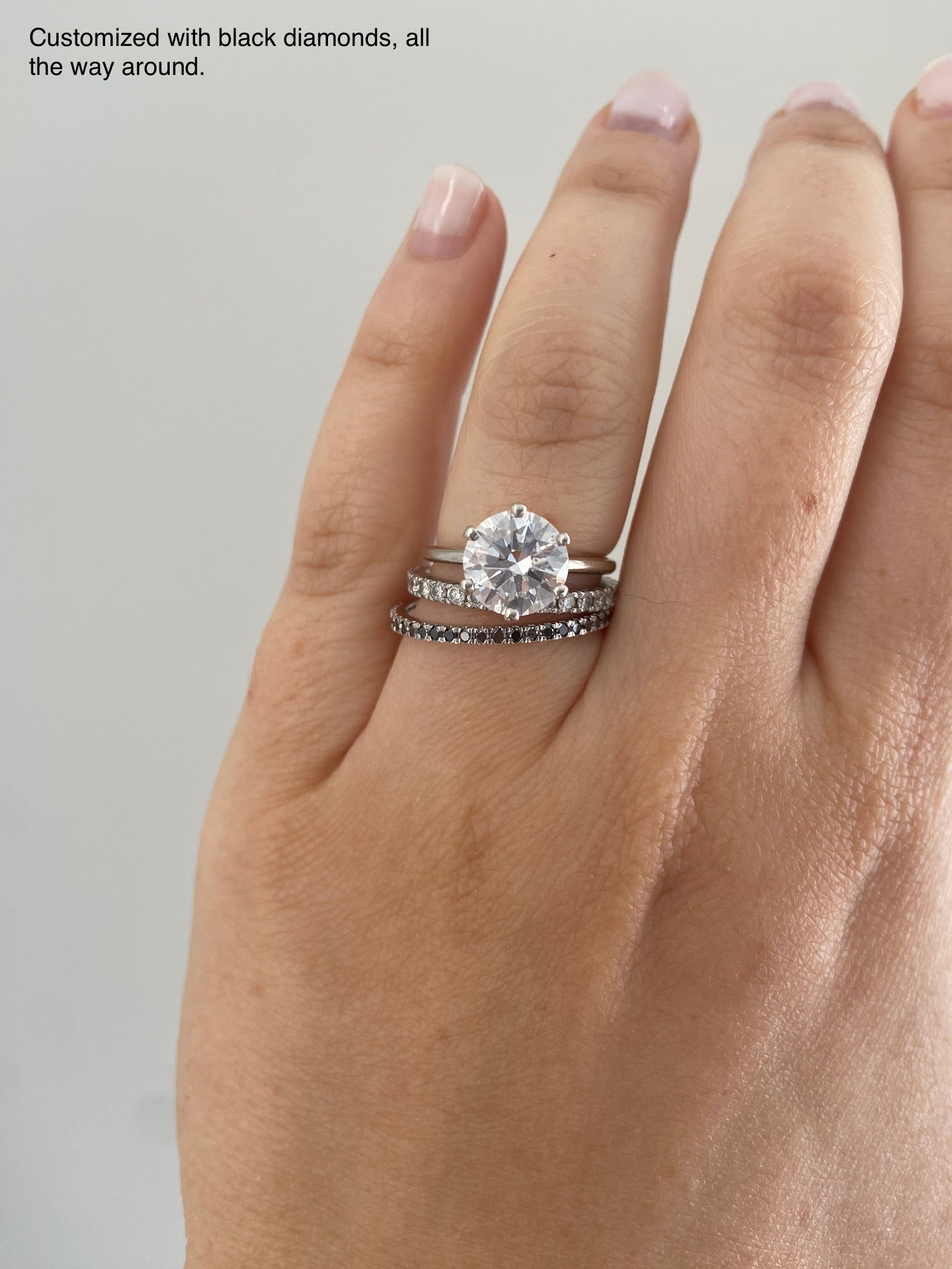 Close-up of a 1.5mm birthstone ring styled with other diamond stacked rings on a person's hand.