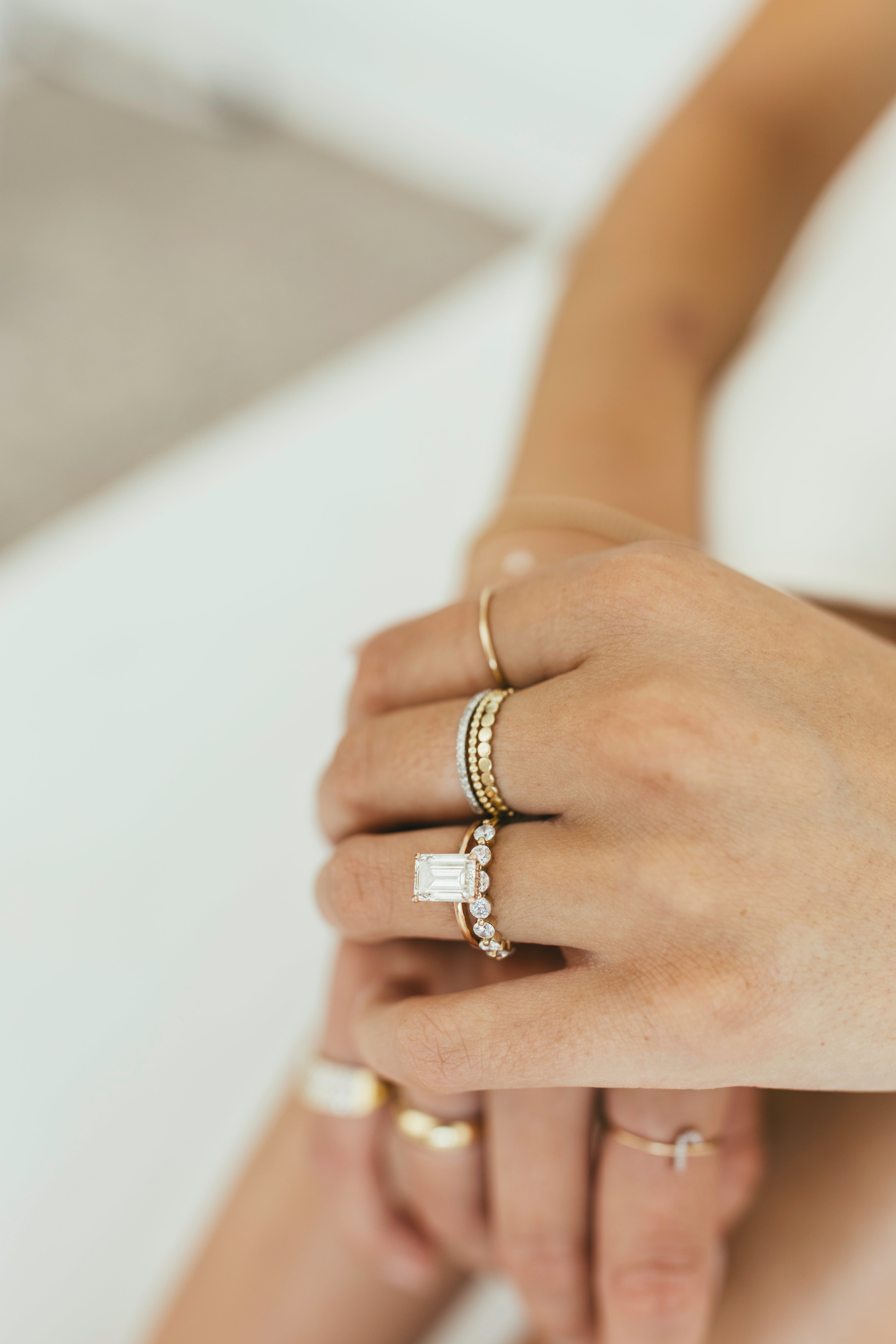 Multiple gold rings styled on a person's hands against a white background.