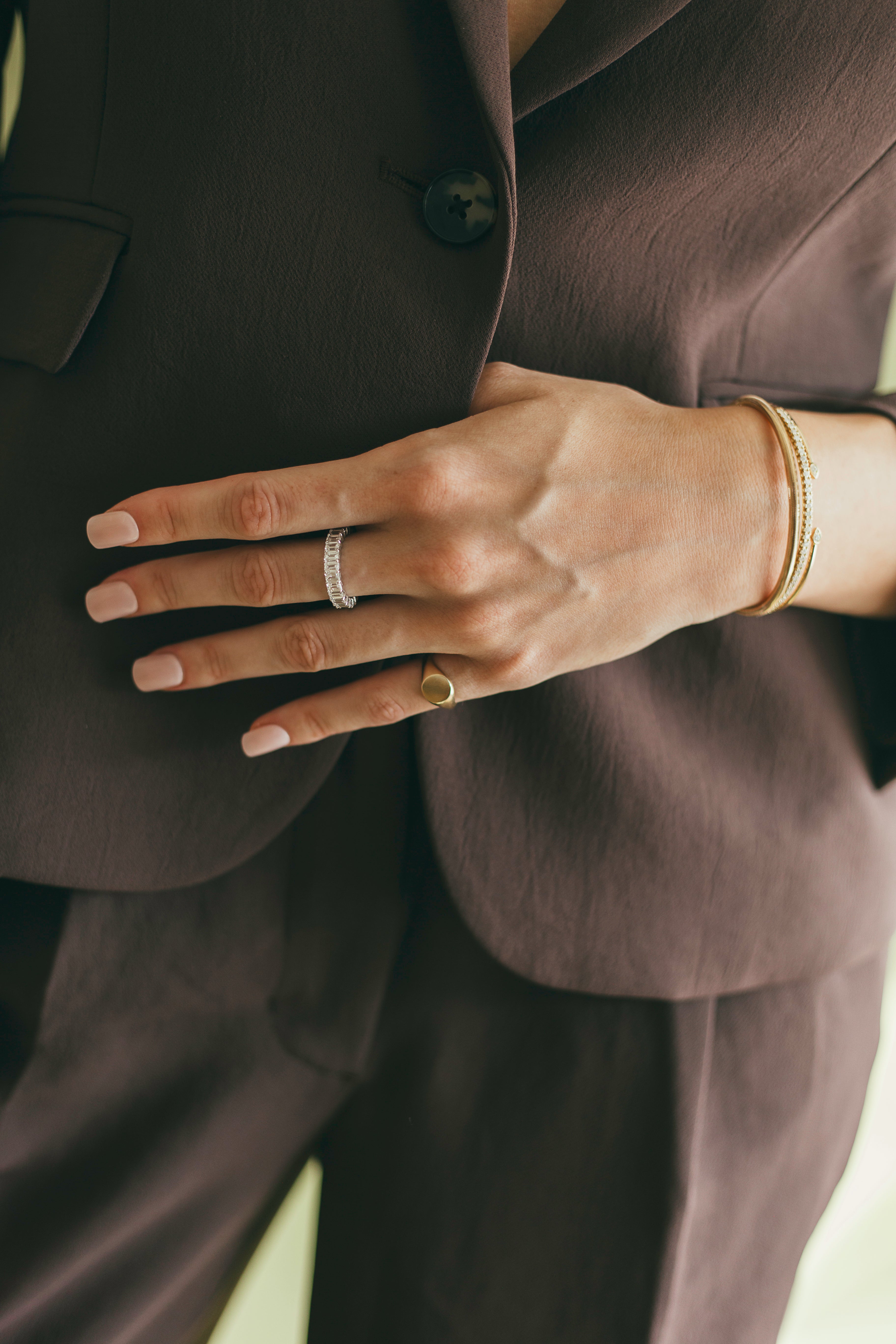 Close-up of a hand wearing gold rings with a dark suit background.
