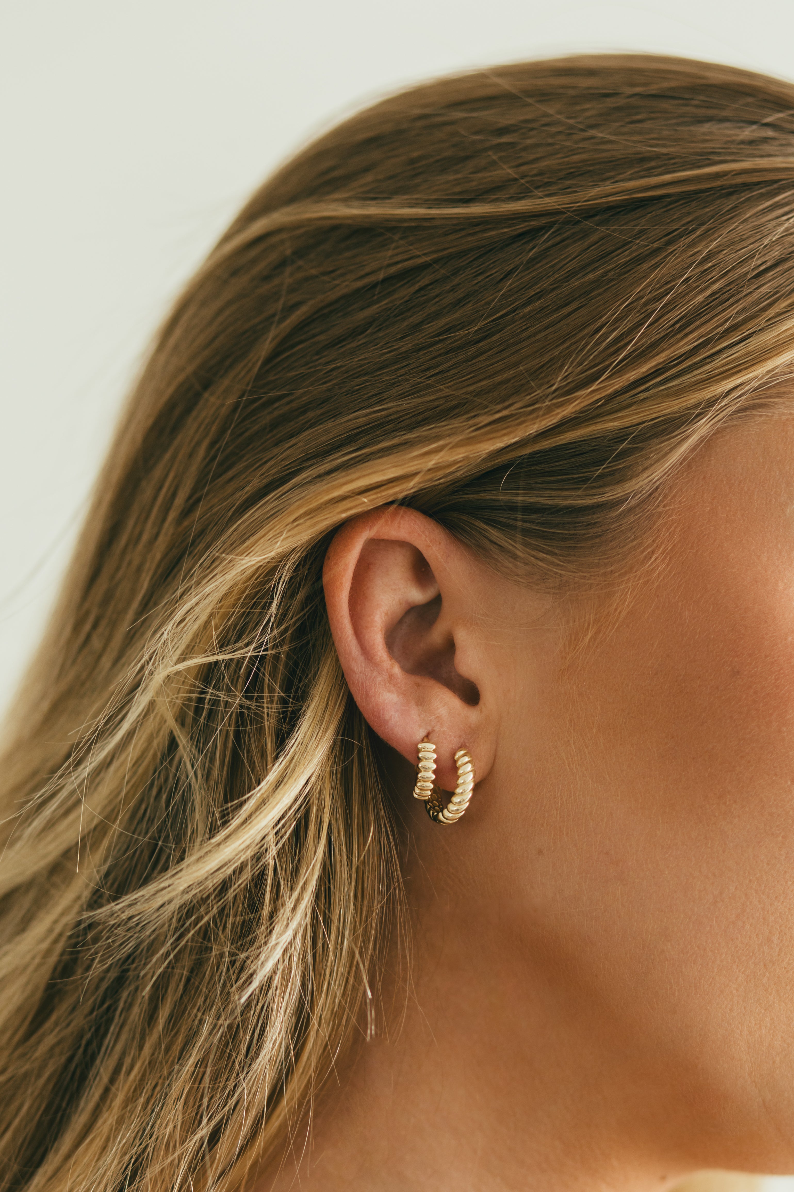close up of ear wearing a stack of textured gold huggies