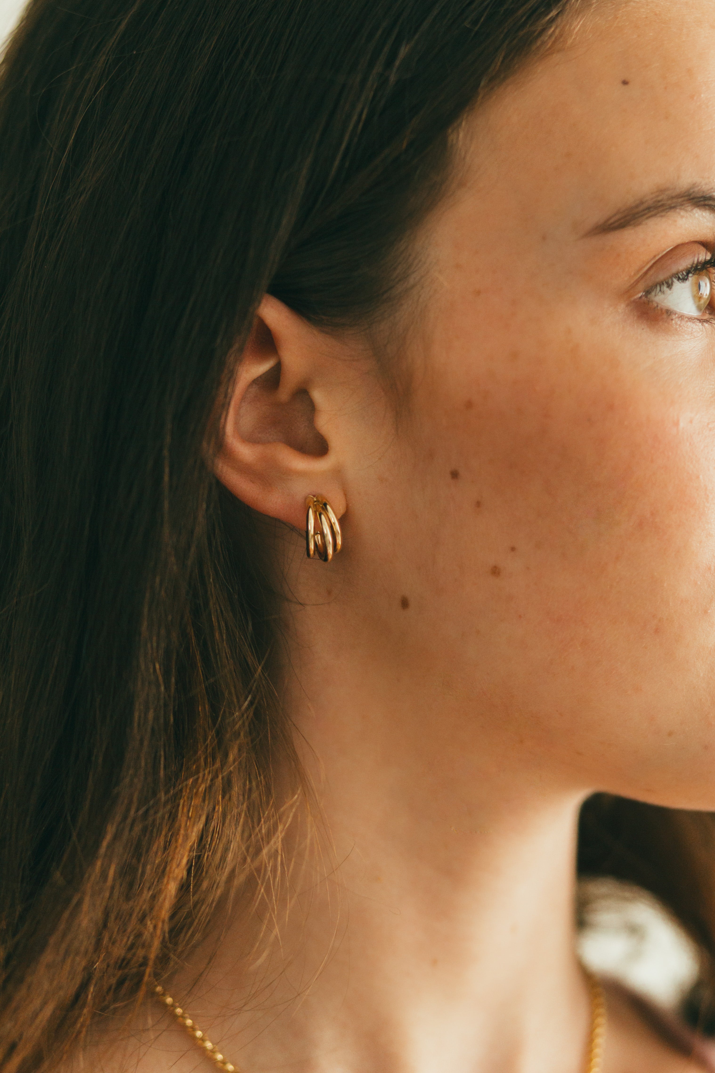 close up of girl wearing gold three row huggie