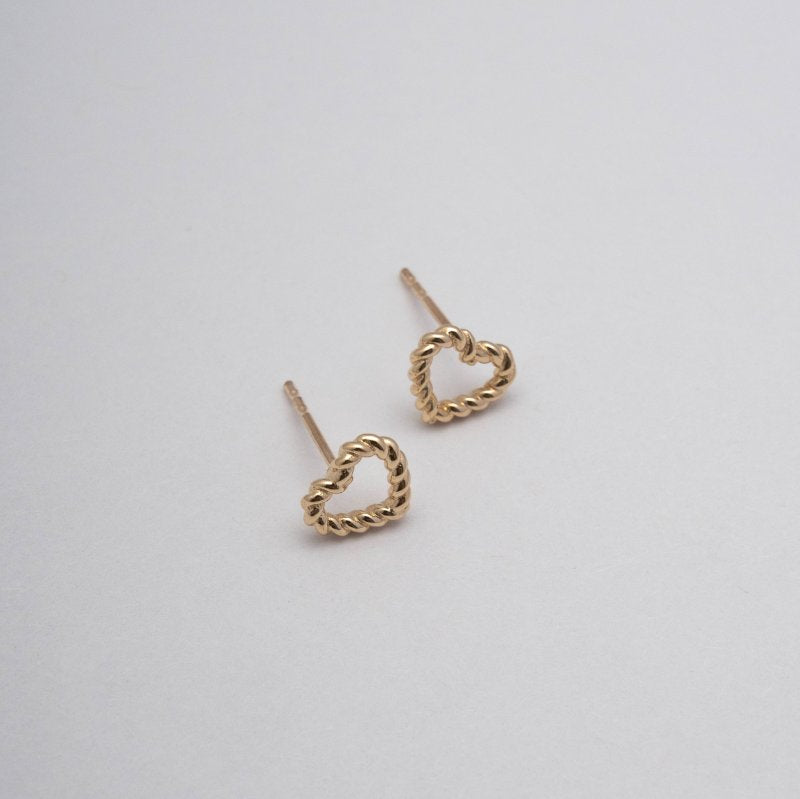 Top view of gold heart-shaped earrings on a light gray background