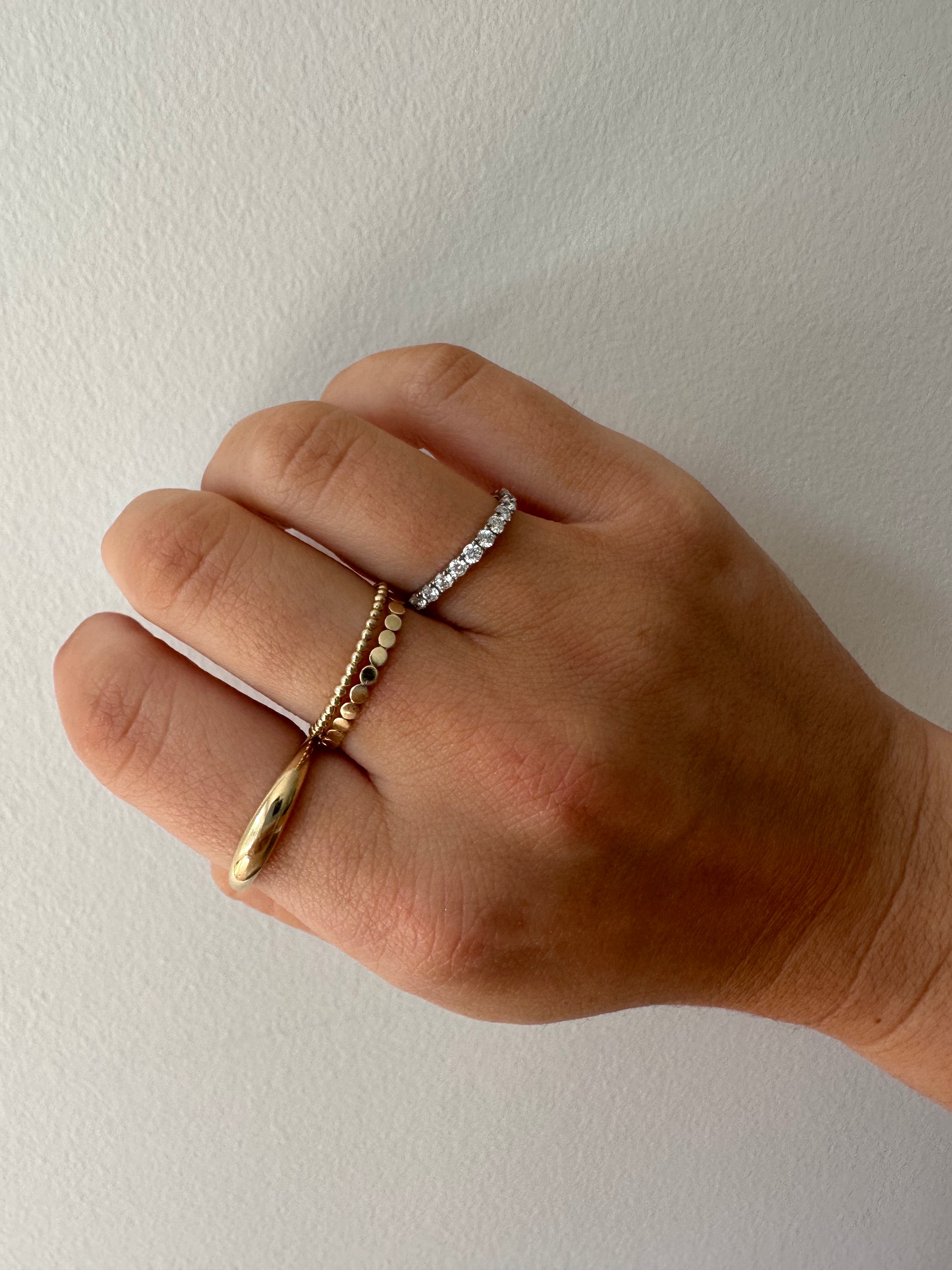 A close-up of a person's hand styled with gold and diamond rings.
