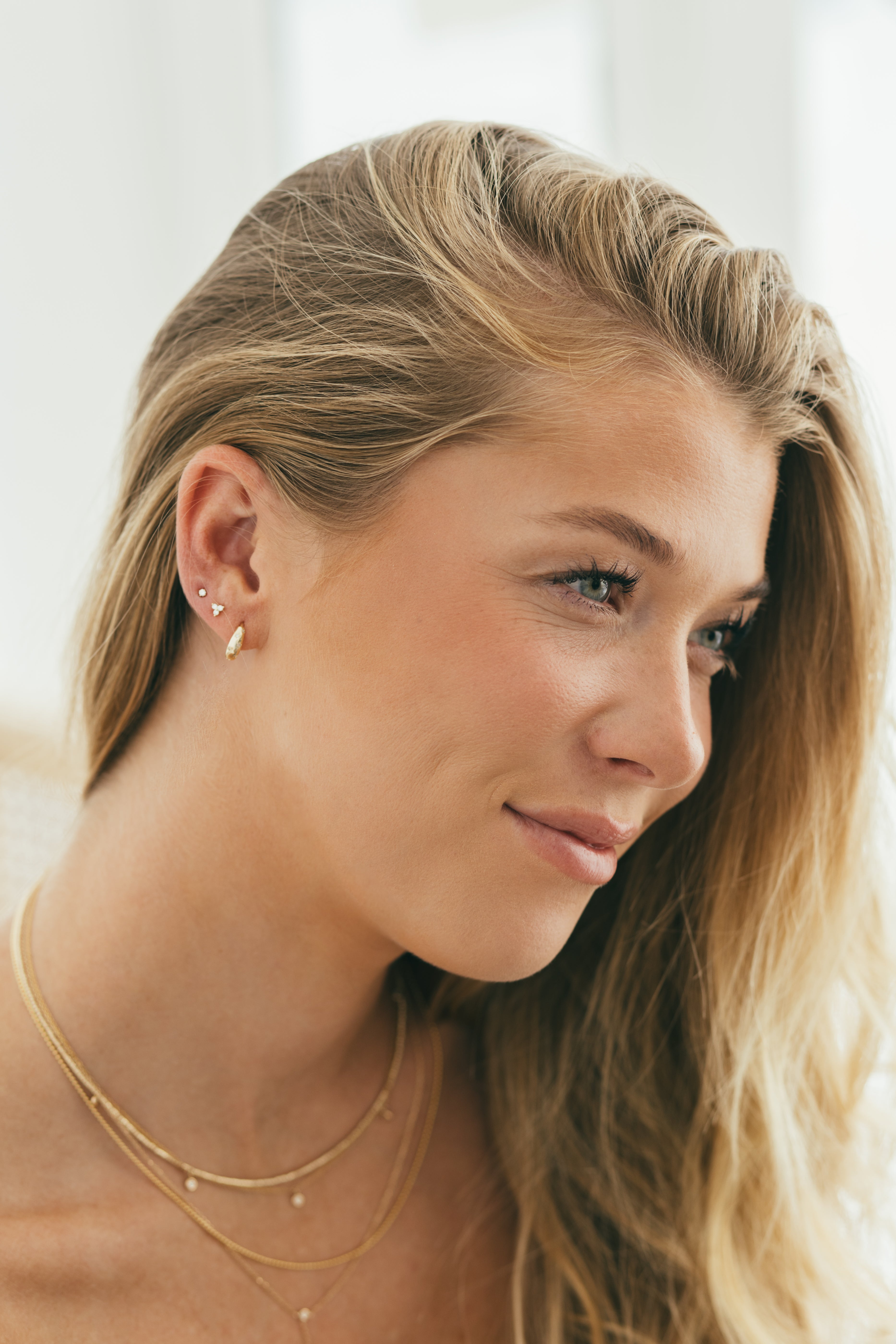 blonde girl wearing an earring stack of gold huggies and diamond studs