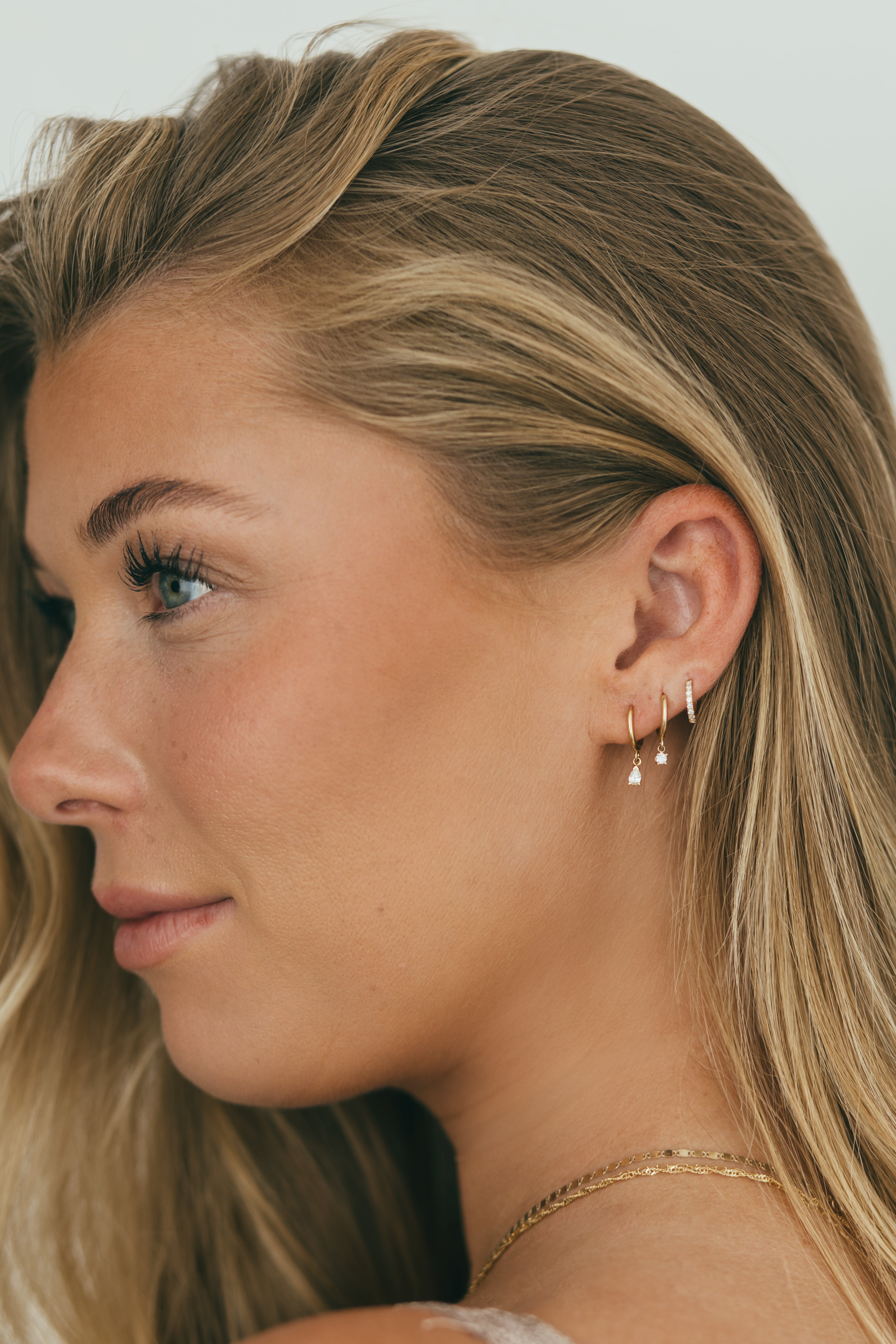 girl wearing stack of dangling diamond huggies