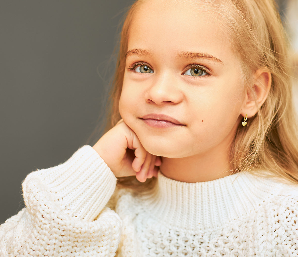 little girl wearing gold dangling heart huggies
