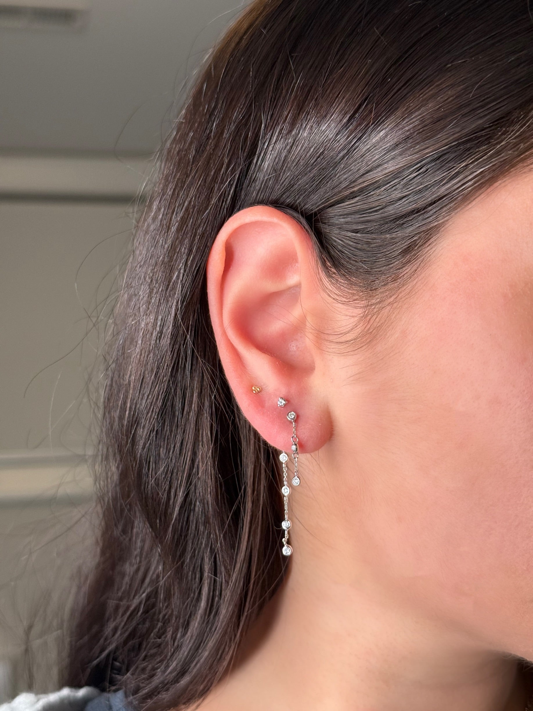close up of person wearing white gold and diamond chain drop earrings 