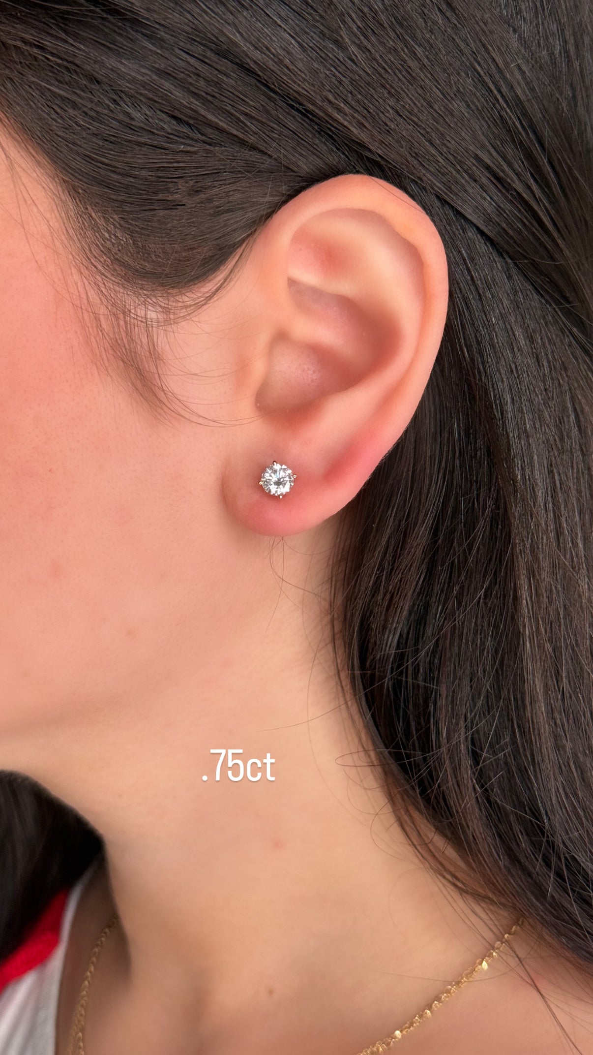 Close-up of an ear wearing a diamond stud earring with '0.75ct' label.