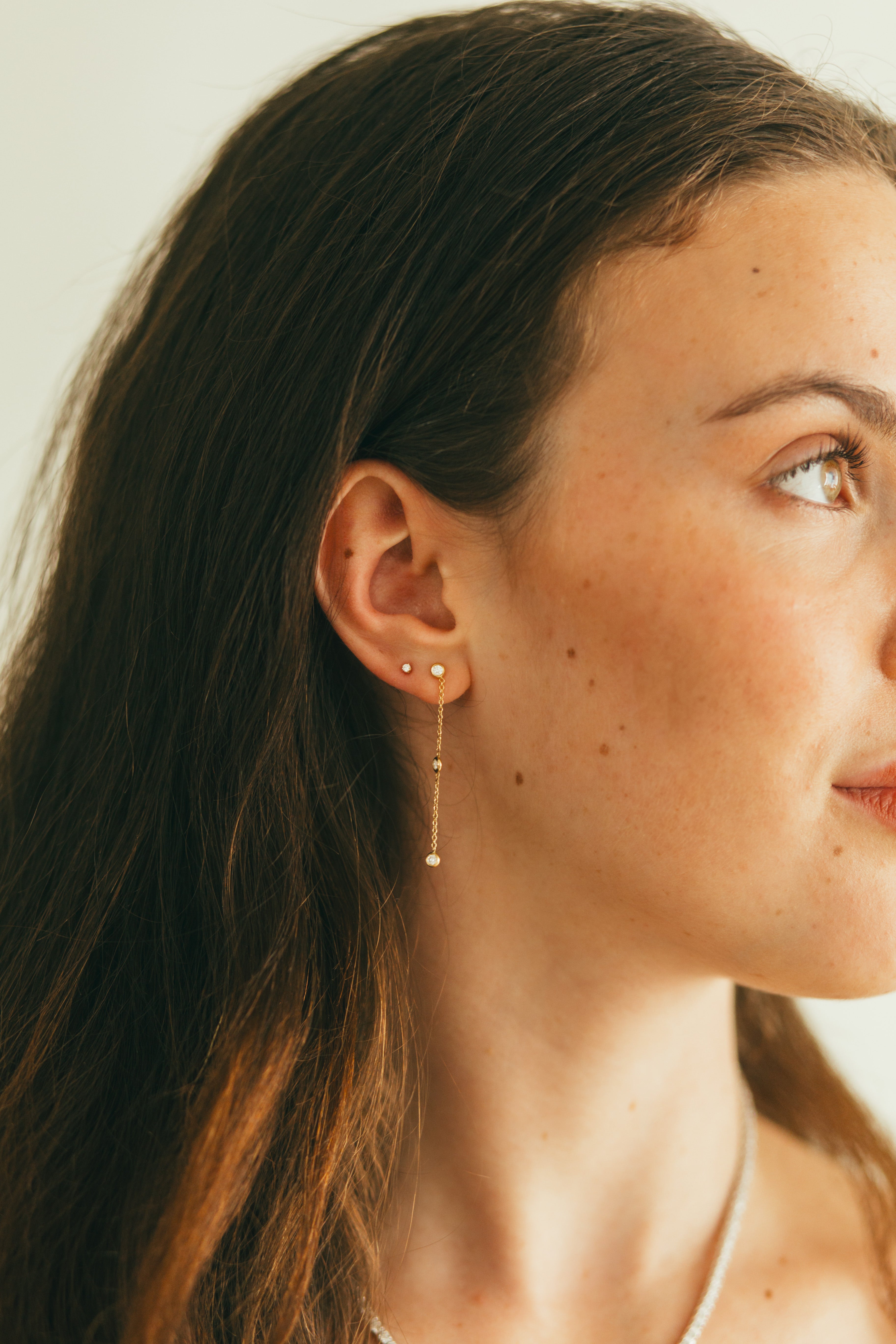 close up of an ear wearing diamond by the yard earrings and diamond studs