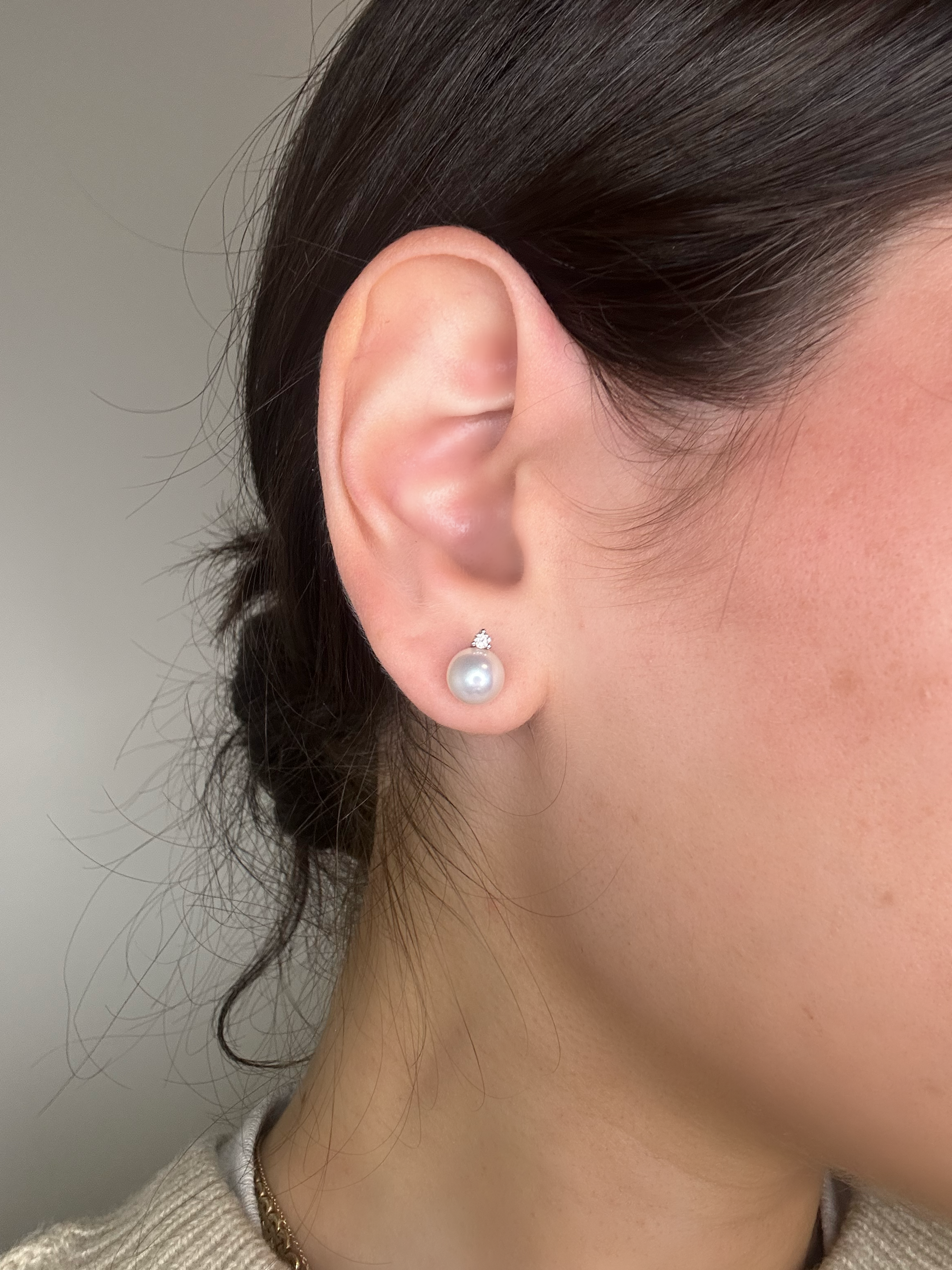 close up of ear wearing natural pearl and diamond studs