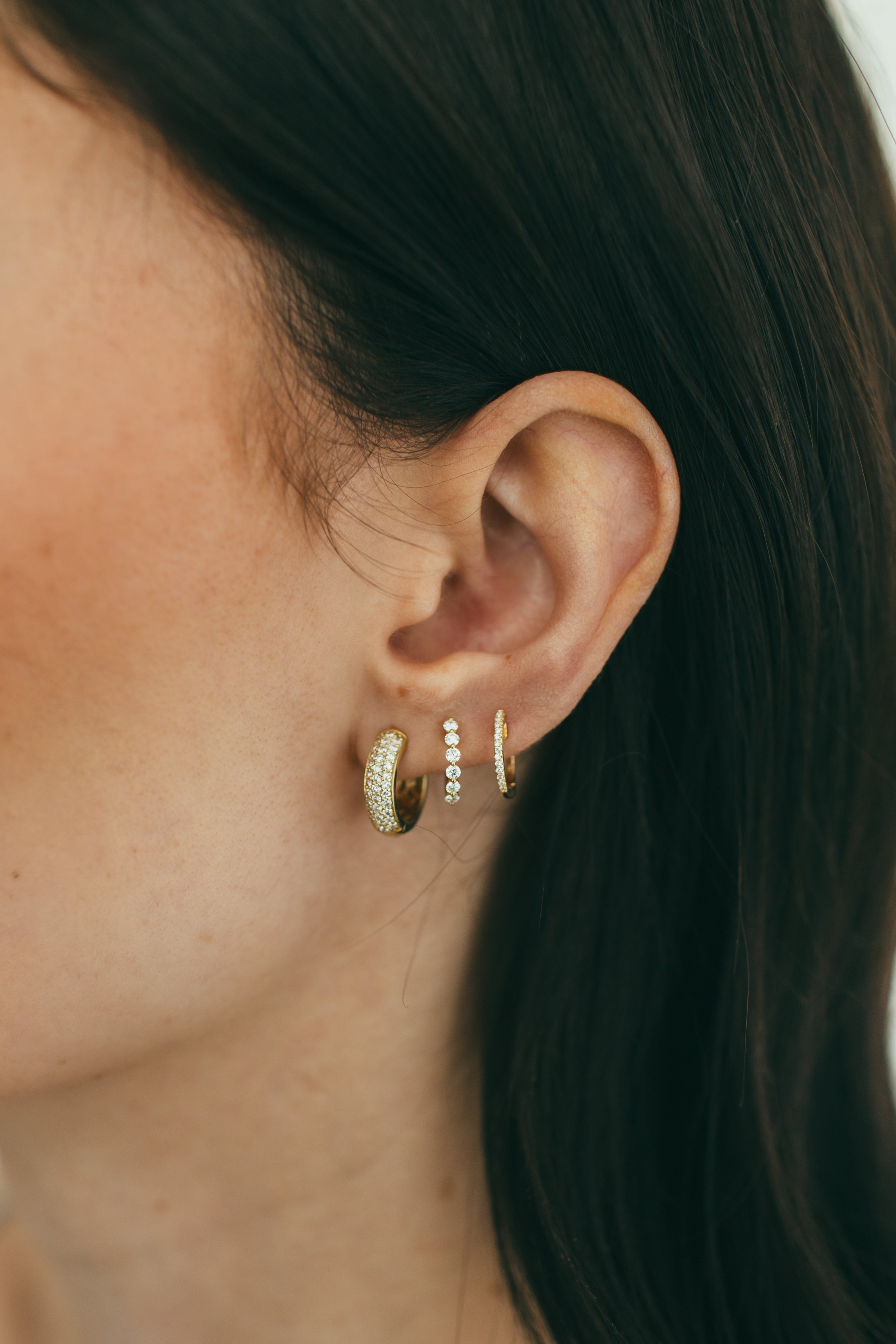 close up of ear wearing diamond huggie stack