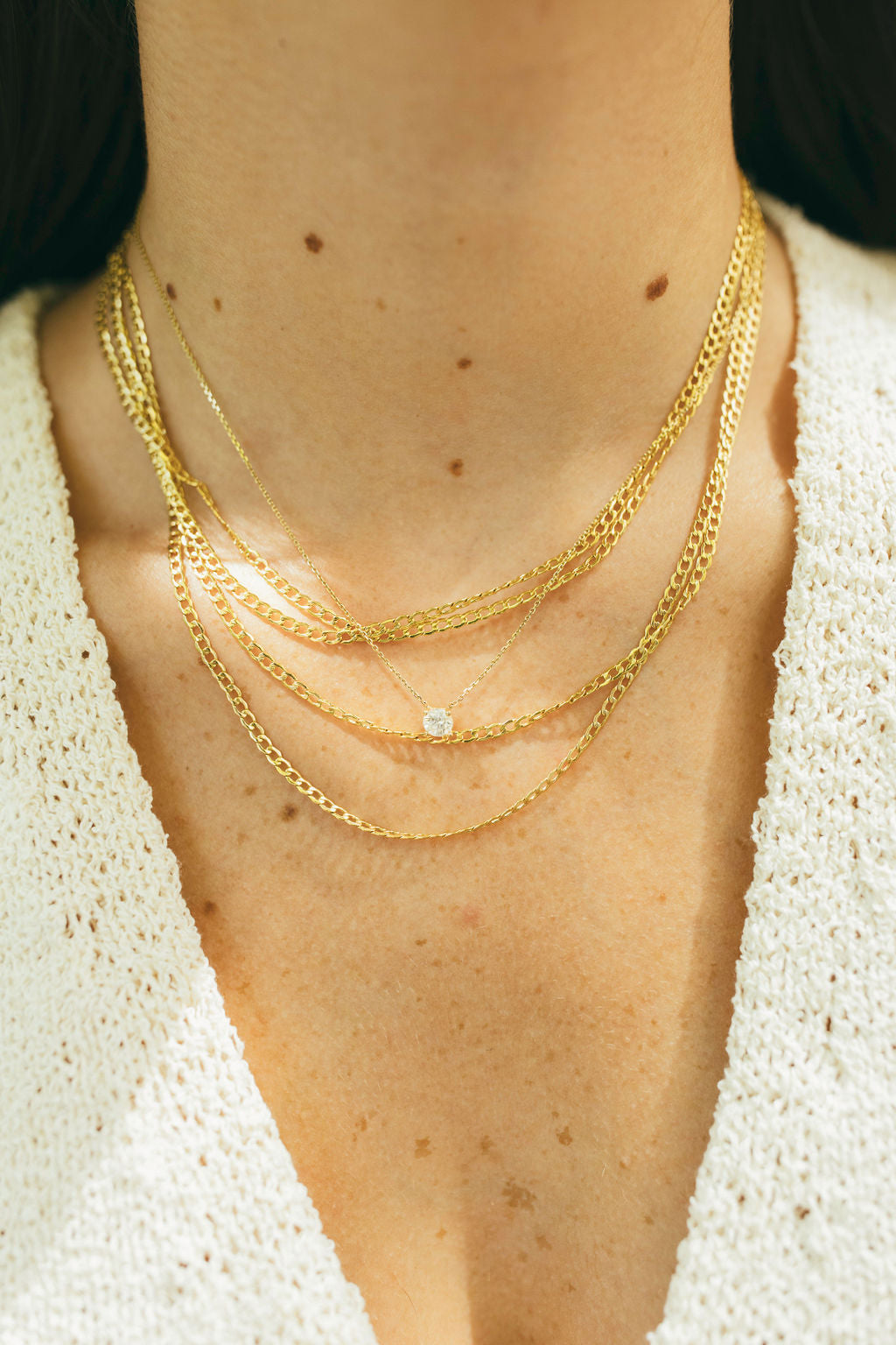 a stack of gold curb chains and a floating diamond necklace 