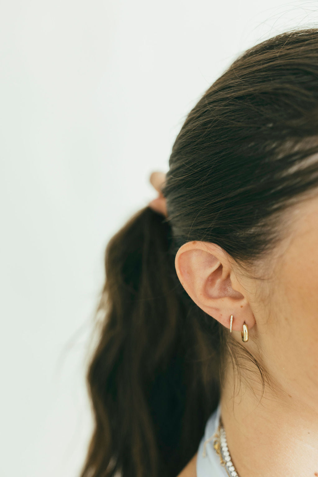 Close-up of a person yellow gold earrings with a plain background