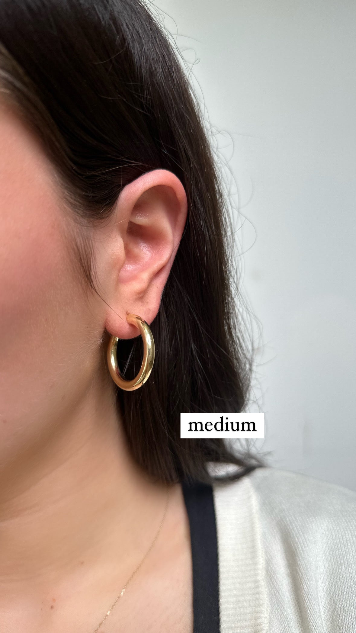 close up of ear wearing gold medium hoop