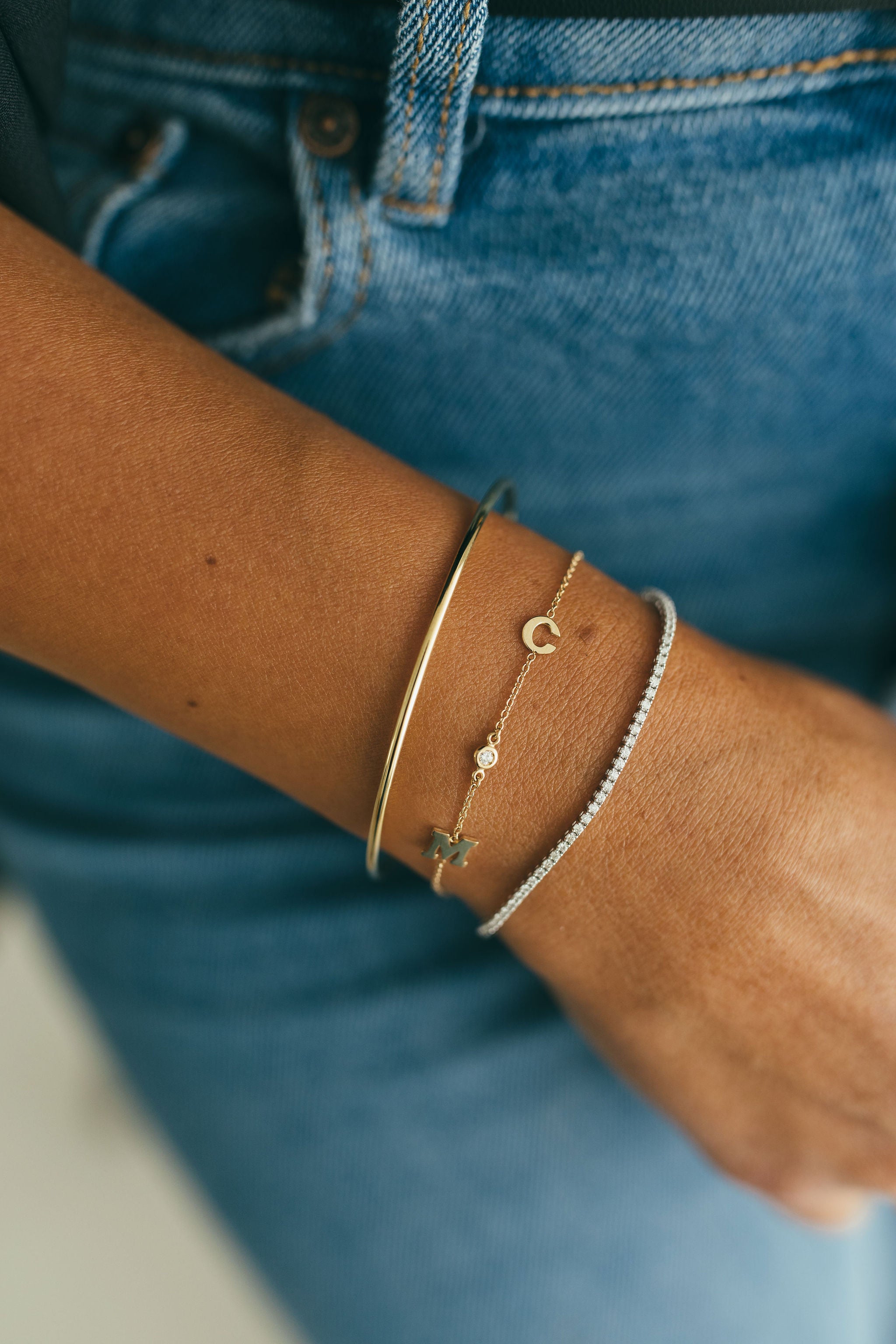 Fashion shot of a model's wrist adorned with Jessica Jewellery's Bold Initial and Diamond Bracelet, emphasizing the unique personalization of initials and diamonds.