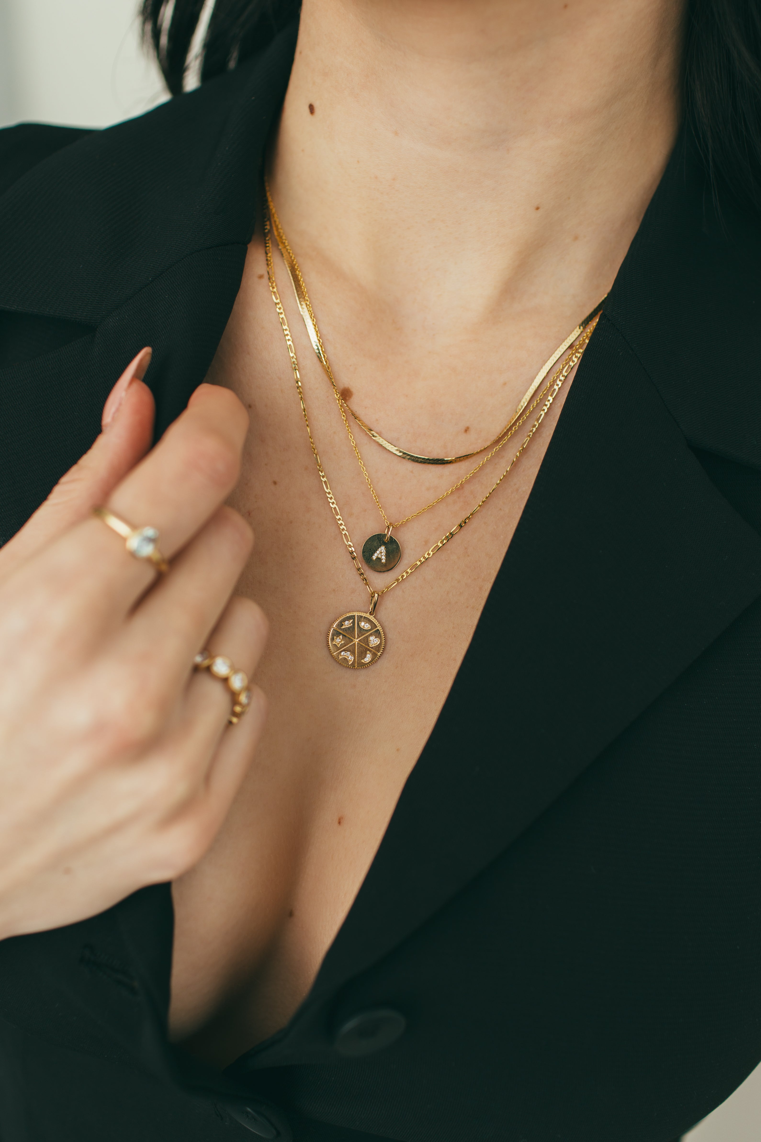 close up of person layering three gold necklaces 