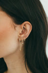 Close-up of model's ear adorned with Jessica Jewellery's Diamond Huggie Earrings featuring elegant diamond drops.