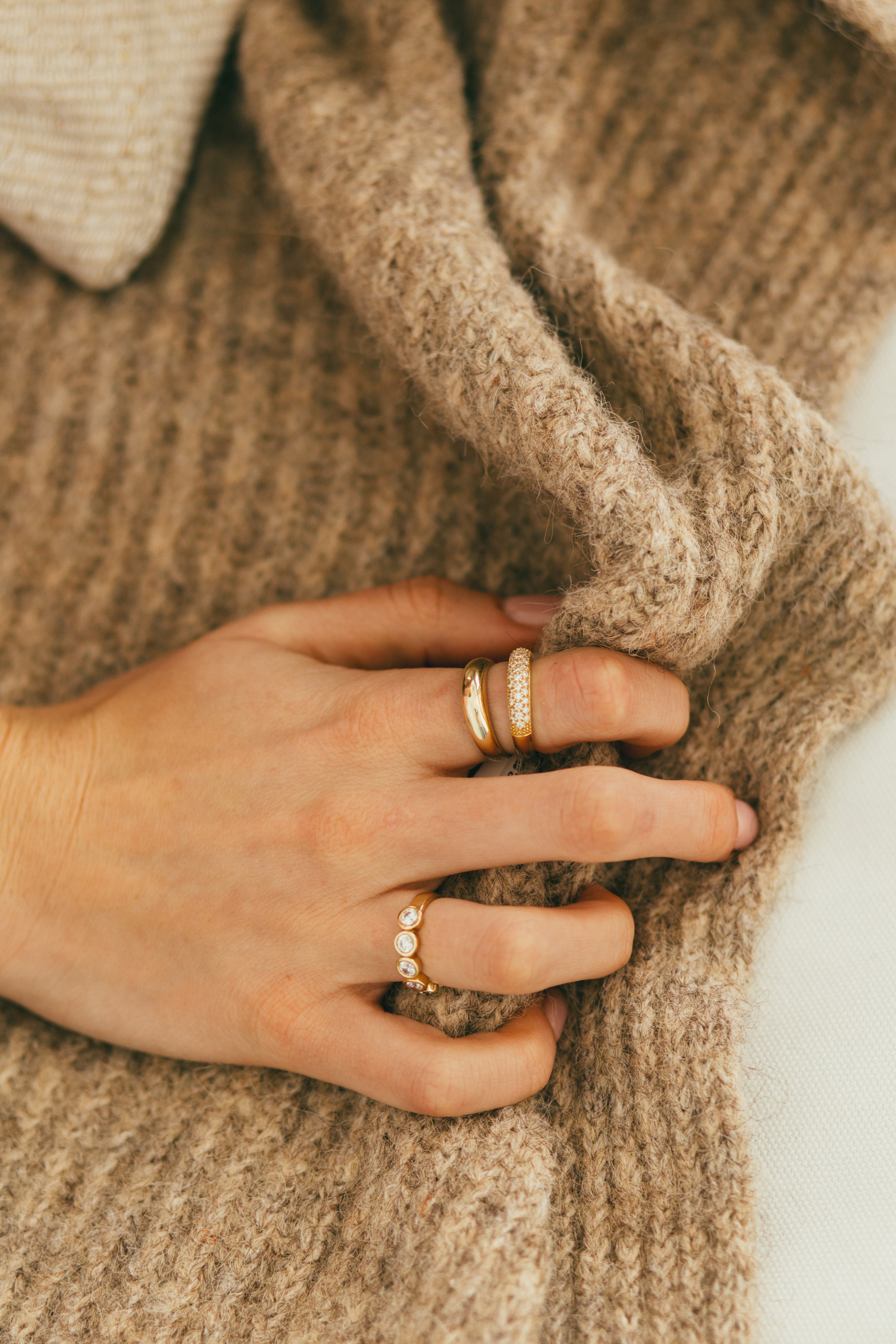 A person clutching a blanket wearing multiple diamond rings.